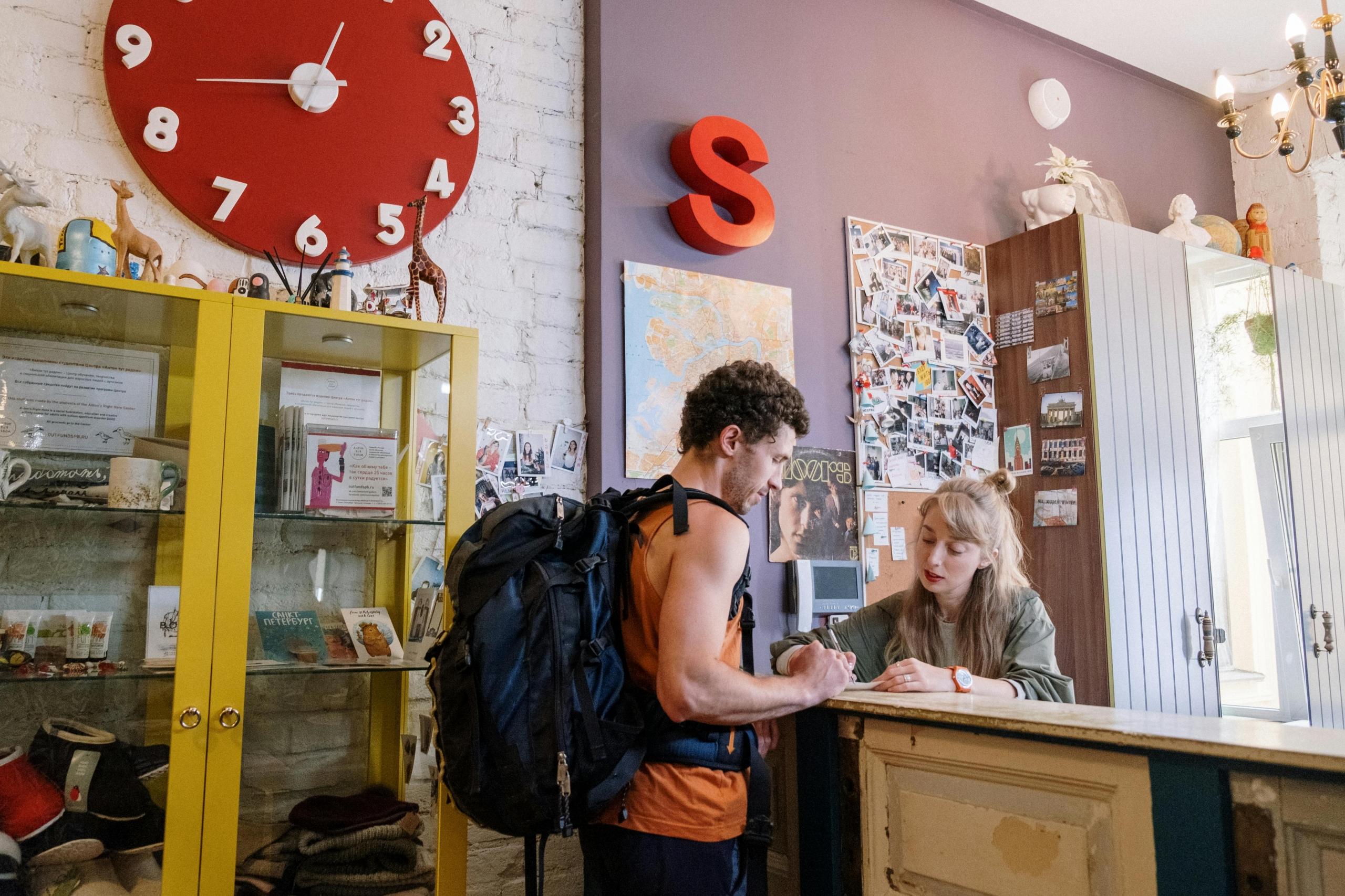 Twee reizigers met rugzakken checken in bij een hostelbalie.