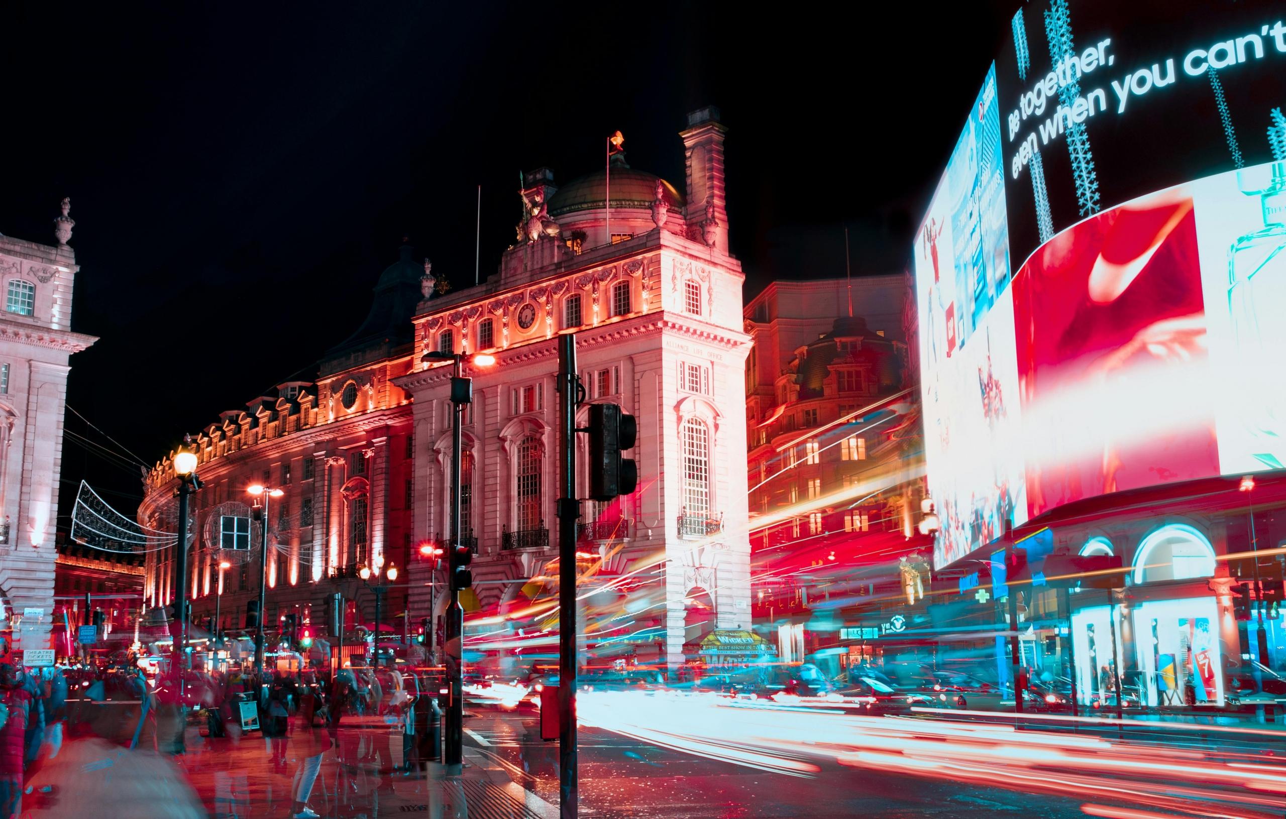 Piccadilly Circus bij nacht met lichtstrepen van voertuigen en neonreclames.
