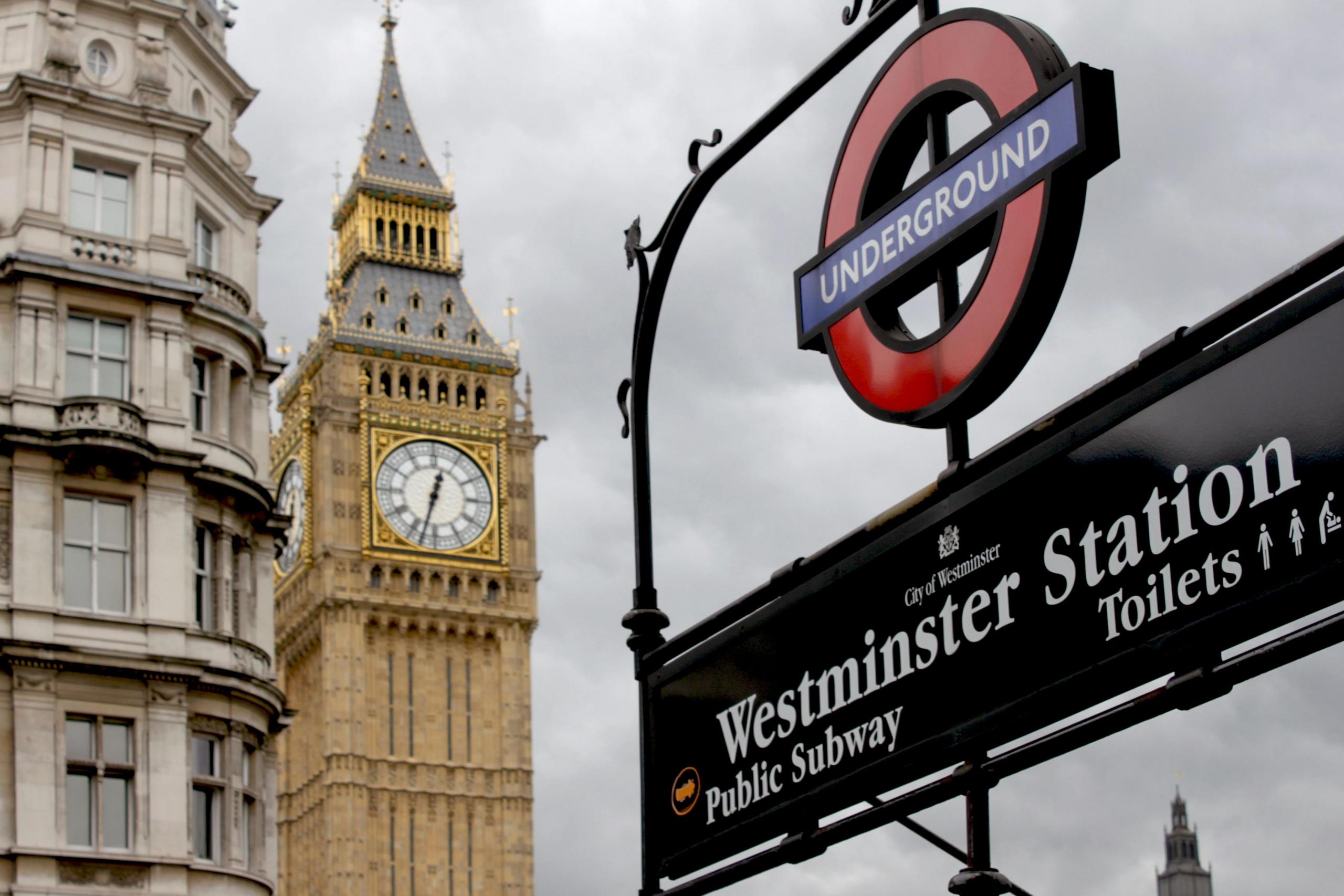 Een metrostationbord van 'Westminster Station' met de klok van de Big Ben op de achtergrond.