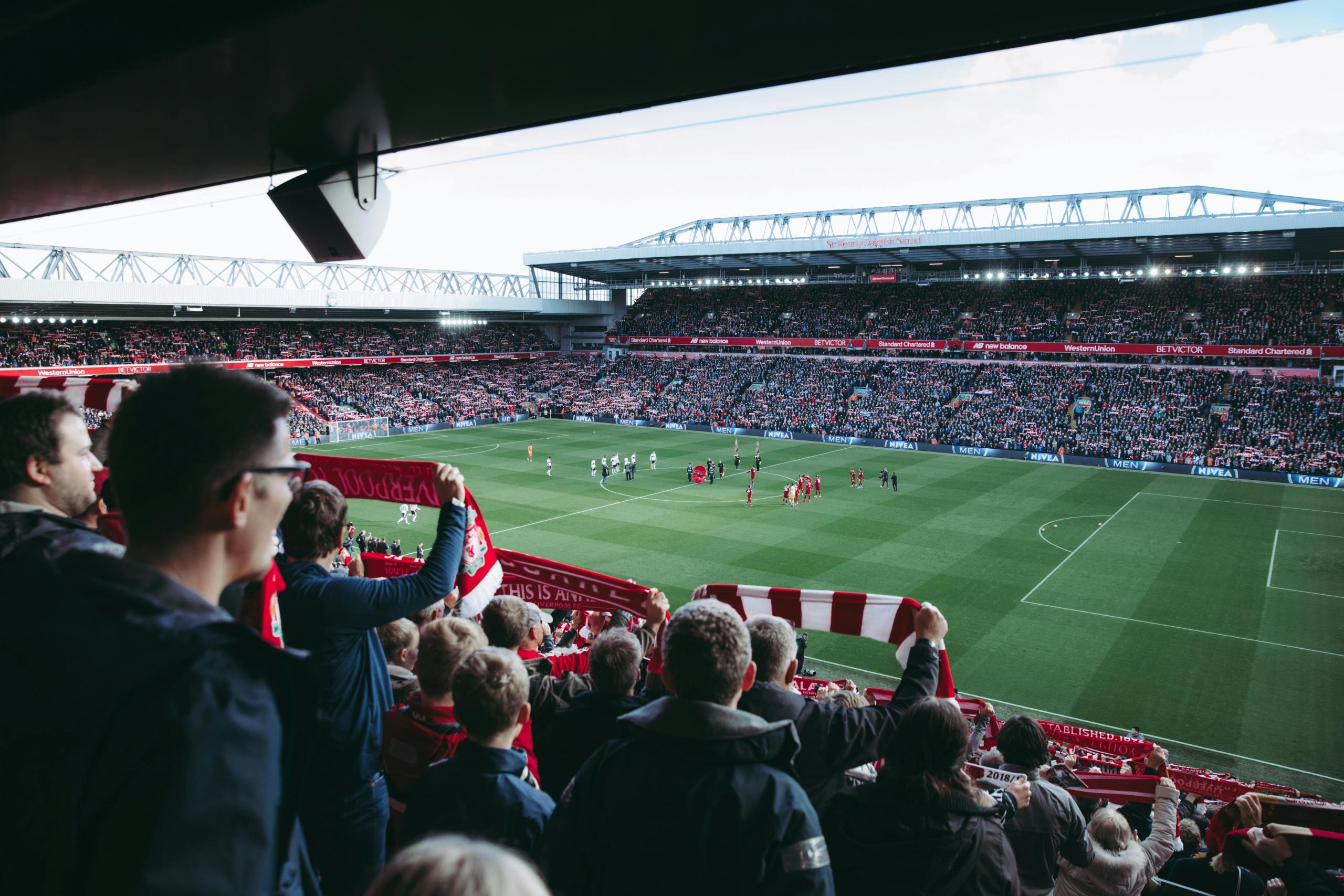 Voetbalfans op de tribune met een uitzicht op het speelveld en de tribunes van het stadion.
