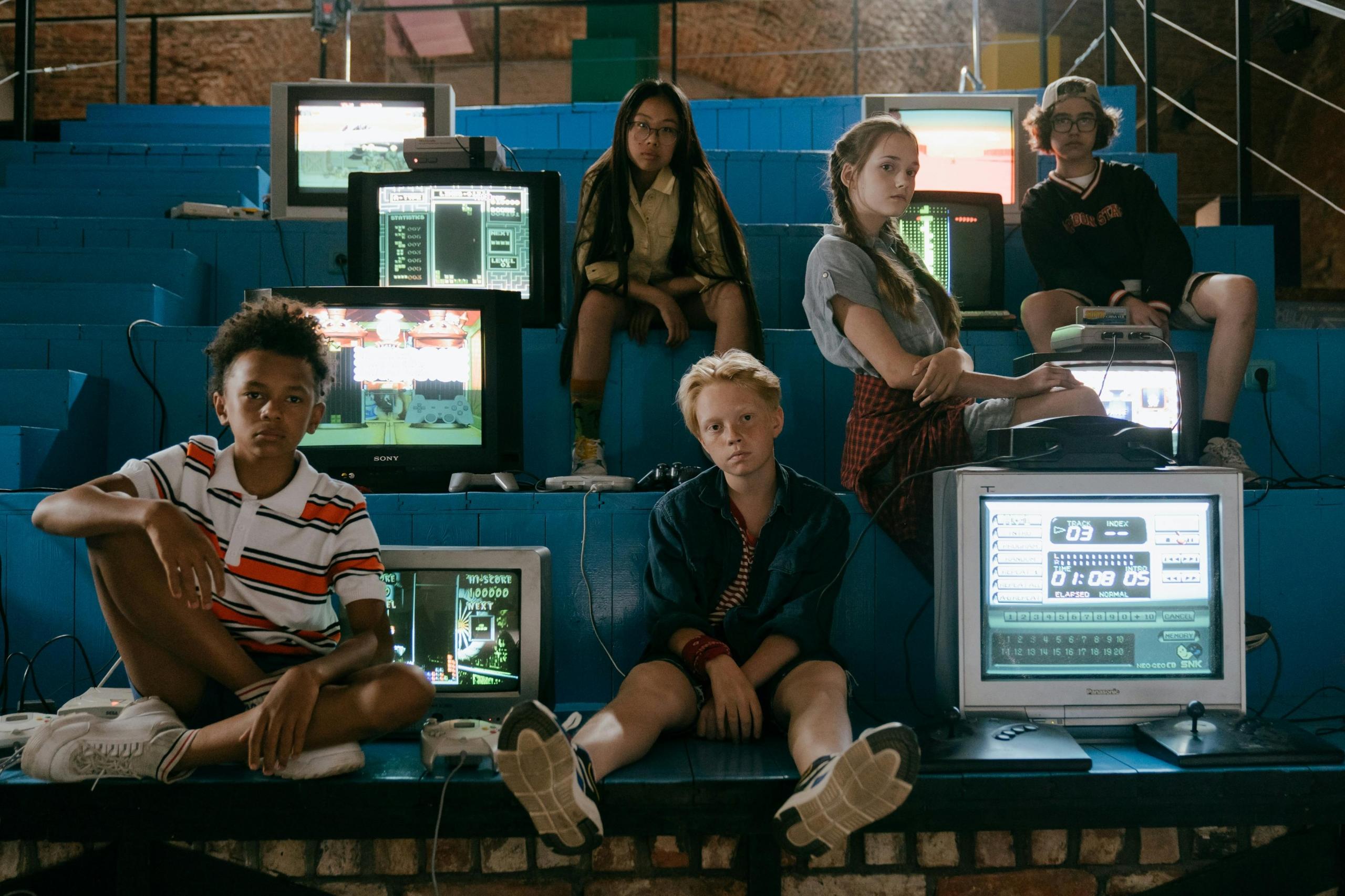 Een groep jongeren zit in een hal met vintage videogames.