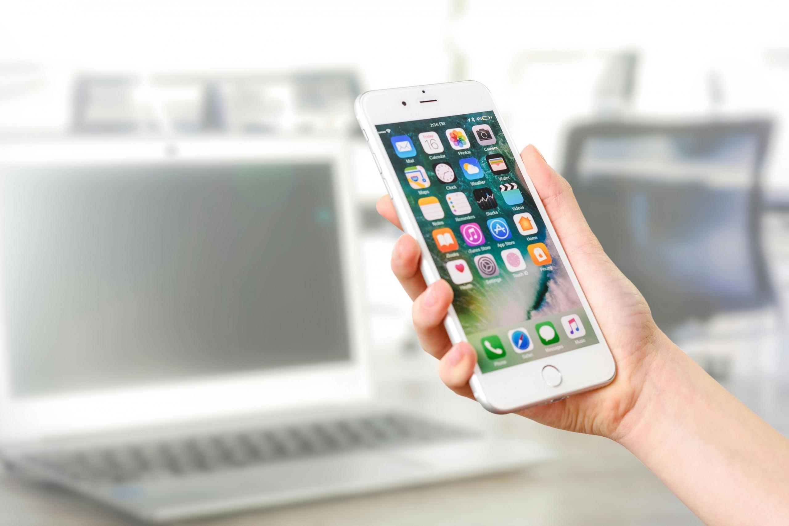 Hand houdt een smartphone vast met een zichtbaar display van apps.