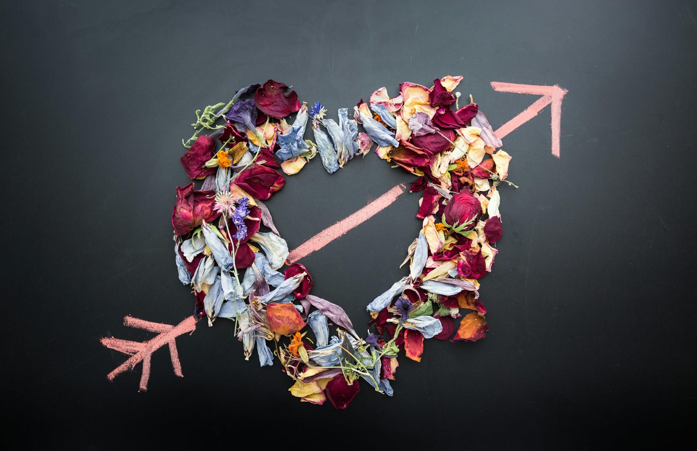 Hart van gedroogde bloemen met pijl op zwarte achtergrond