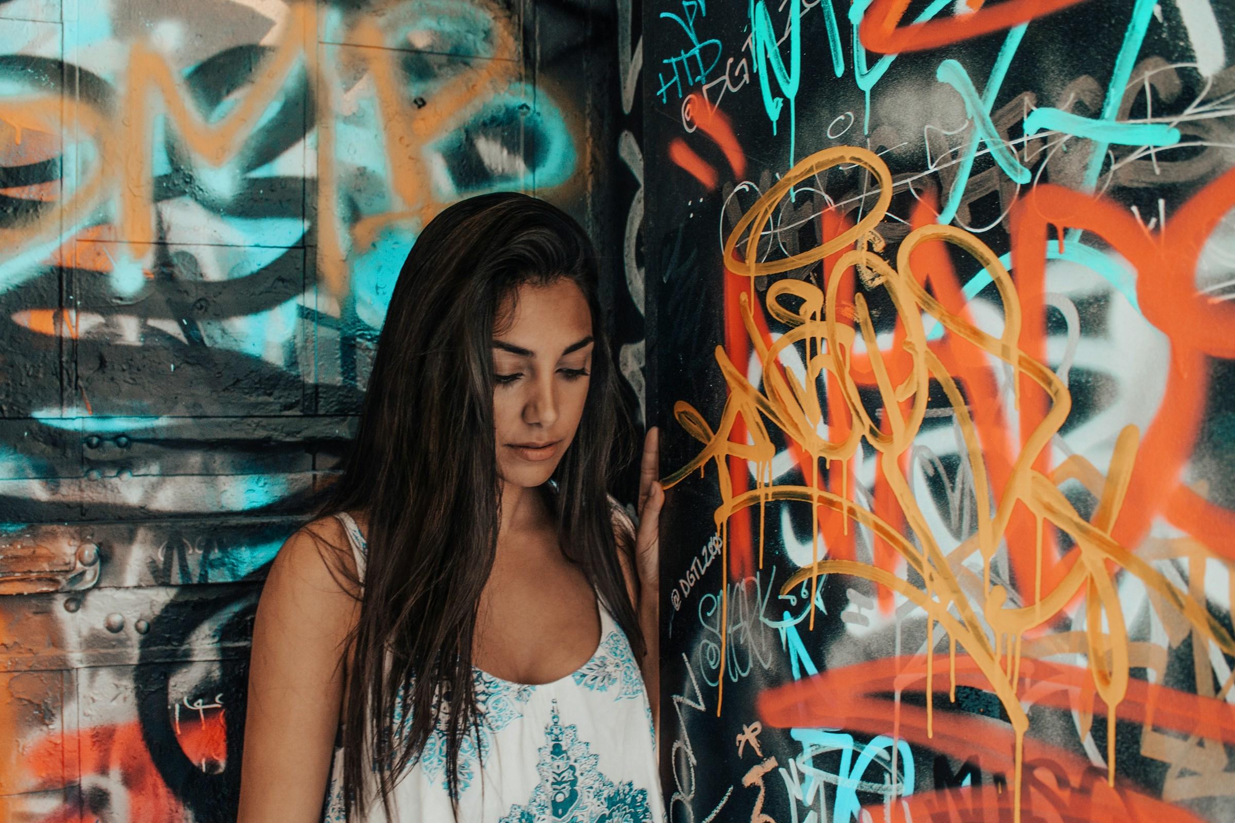 Persoon met neergeslagen ogen voor een graffiti achtergrond