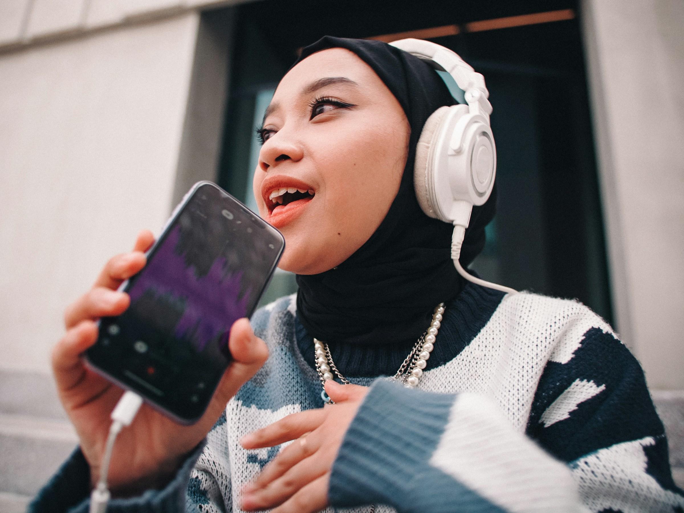 Persoon met koptelefoon en IPhone voor mond