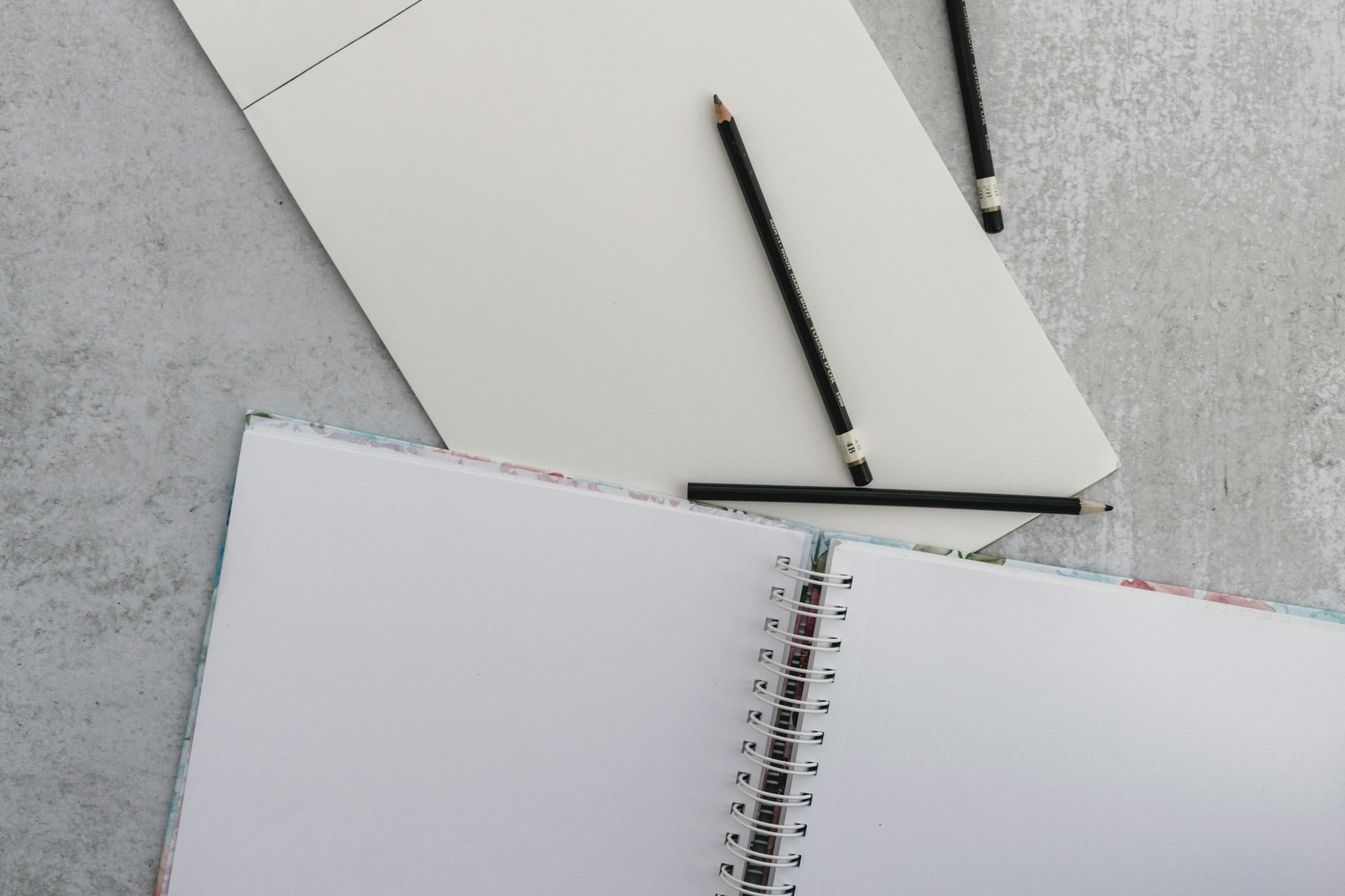Wit papier en zwarte potloden op grijze ondergrond