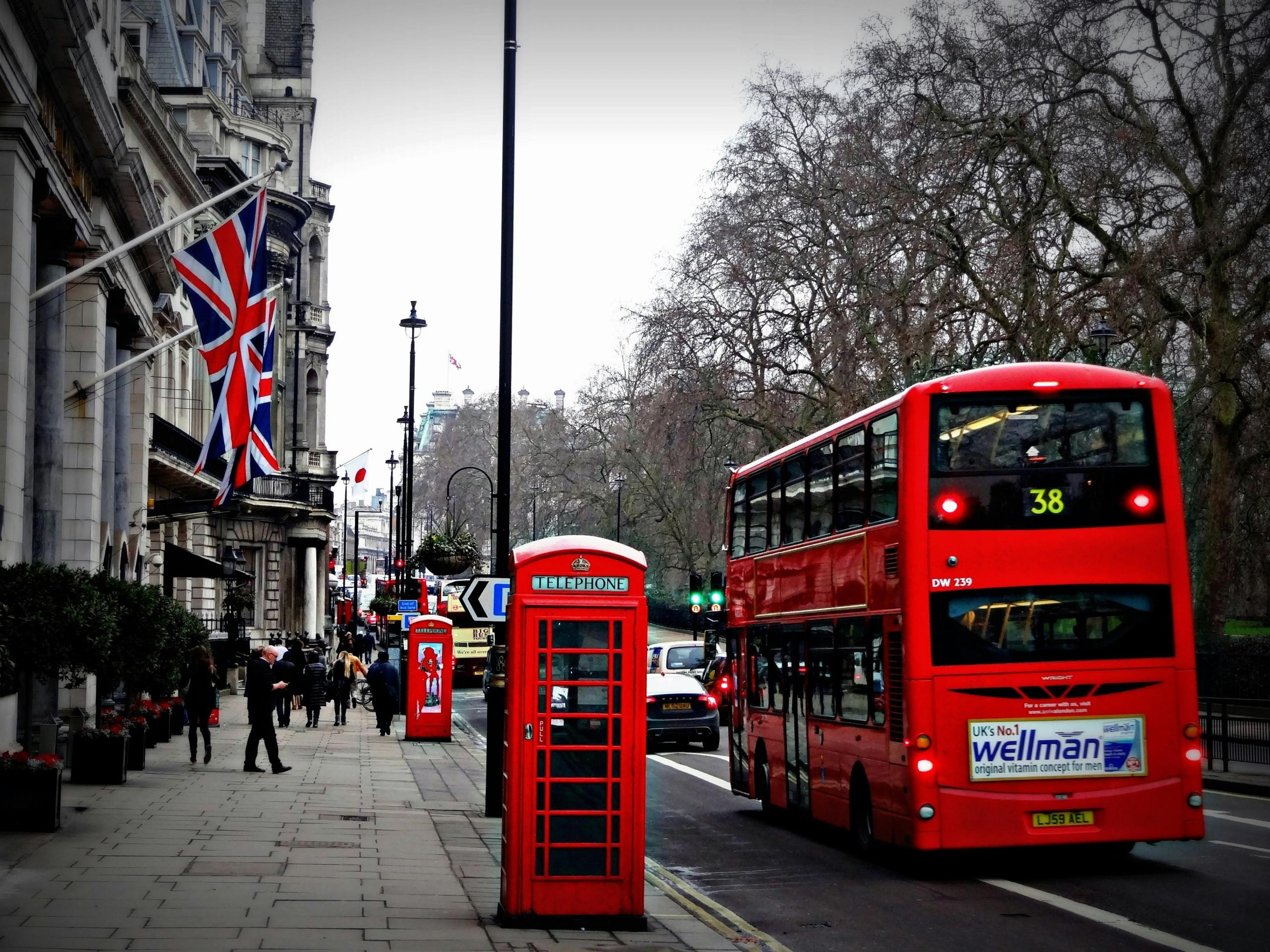 Een typisch Londens straatbeeld met een rode dubbeldekkerbus, een telefooncel en een wapperende Britse vlag.