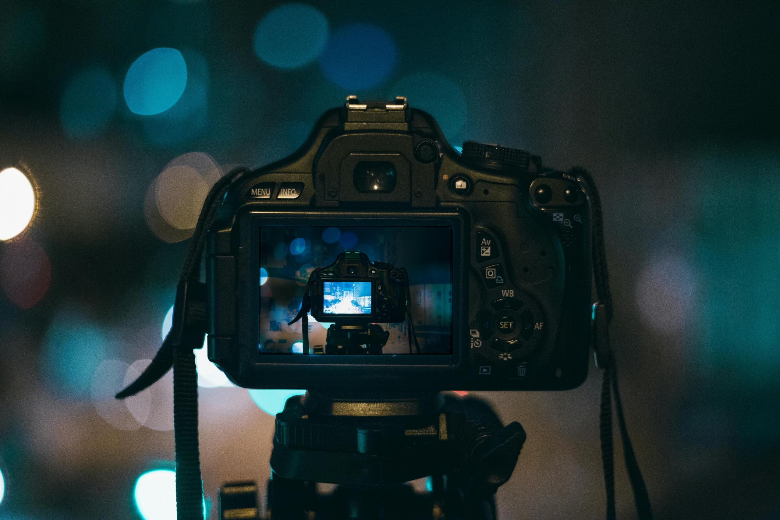 Een digitale camera op een statief filmt een straatscène 's nachts.