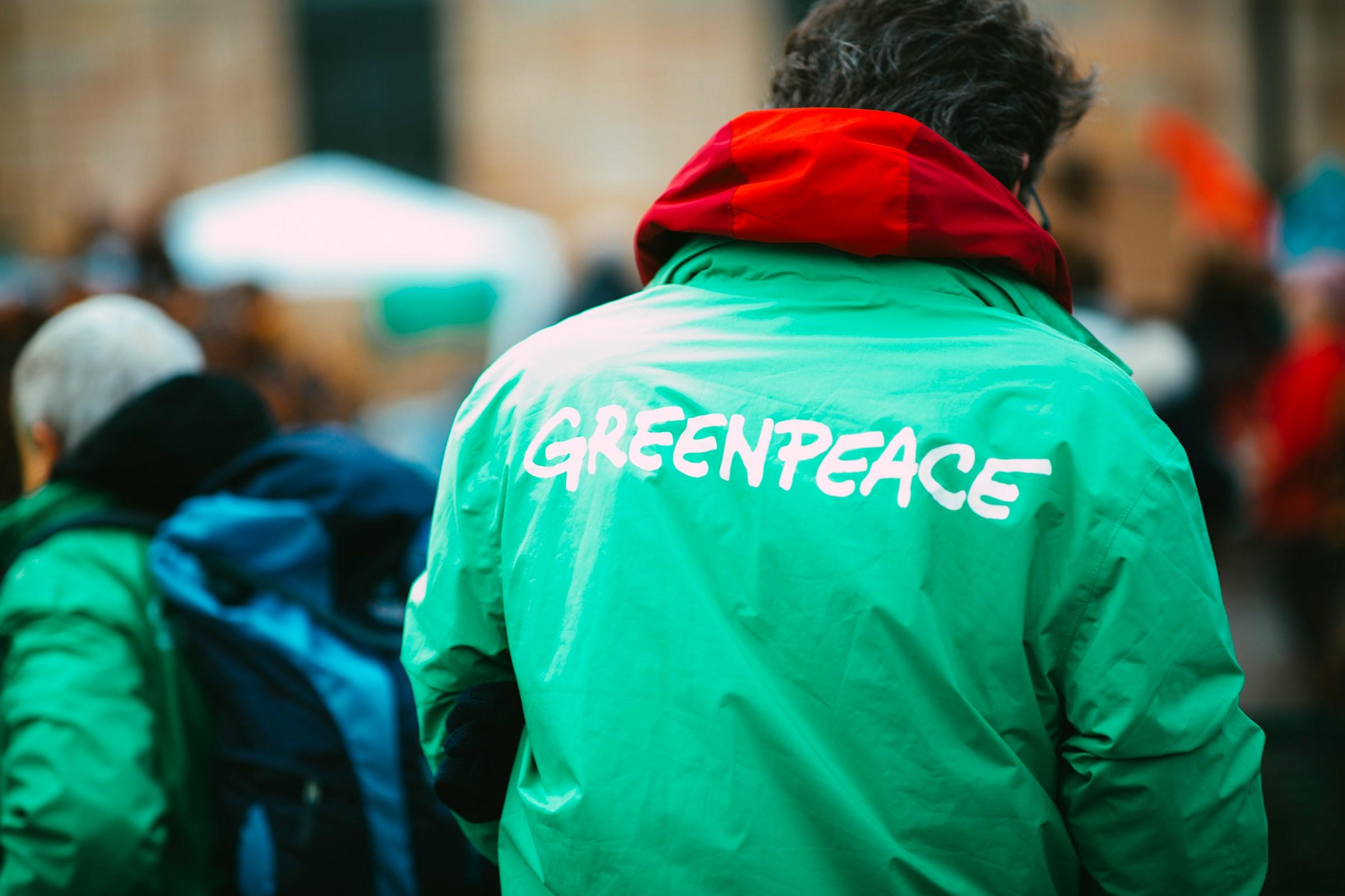 Persoon met groen jack met de naam Greenpeace op de rug
