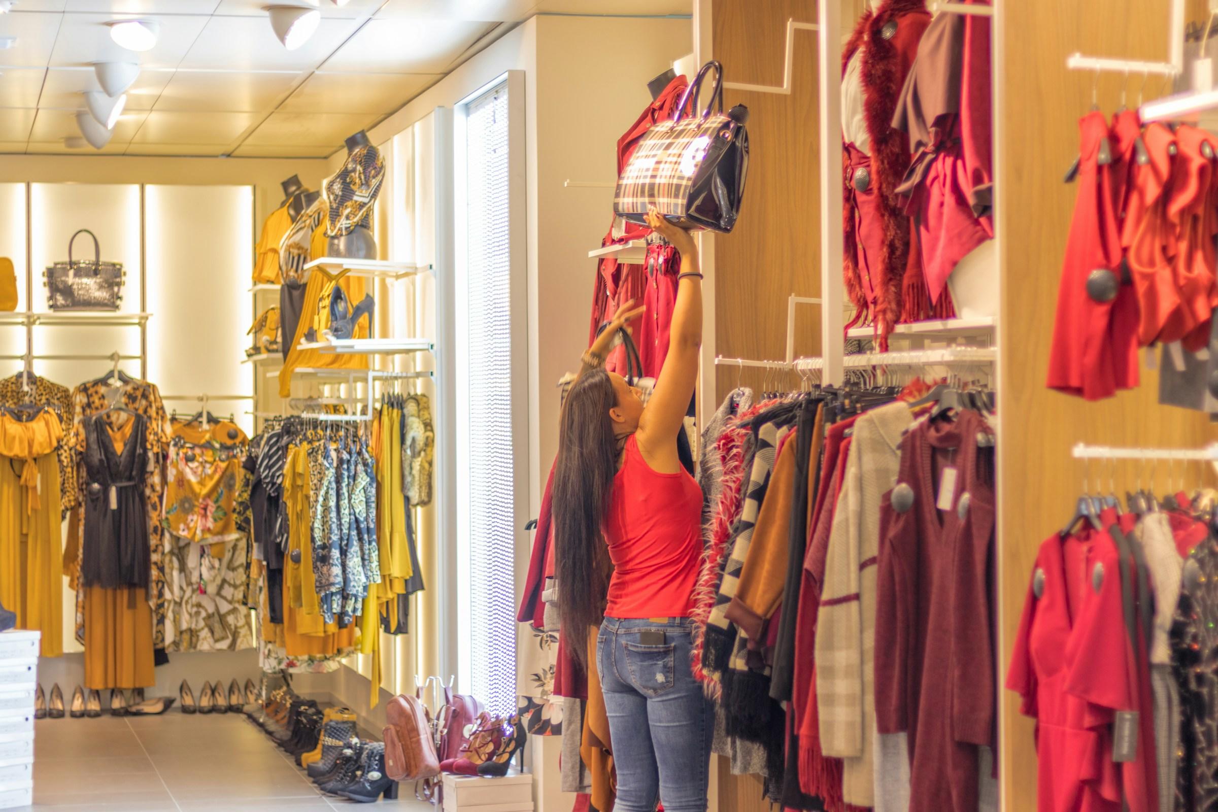 Persoon hangt tas op in kledingwinkel
