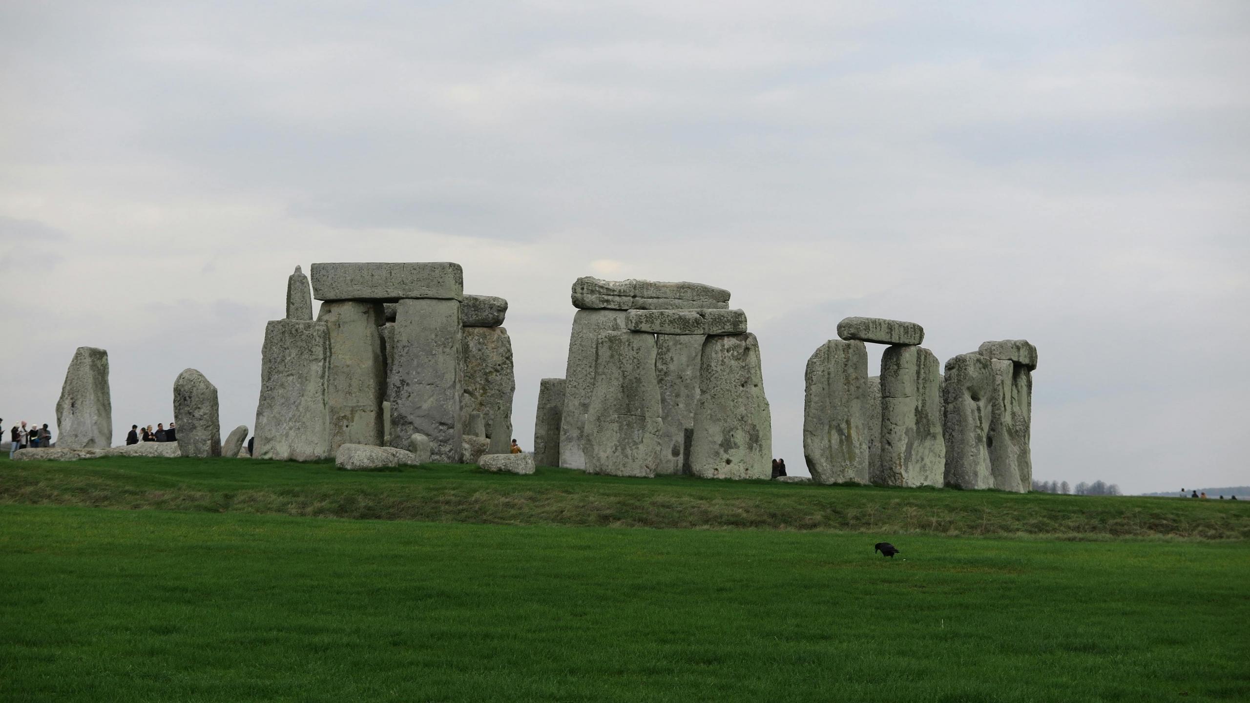 Stonehenge bij schemerlicht met bezoekers die tussen de enorme stenen constructies lopen.