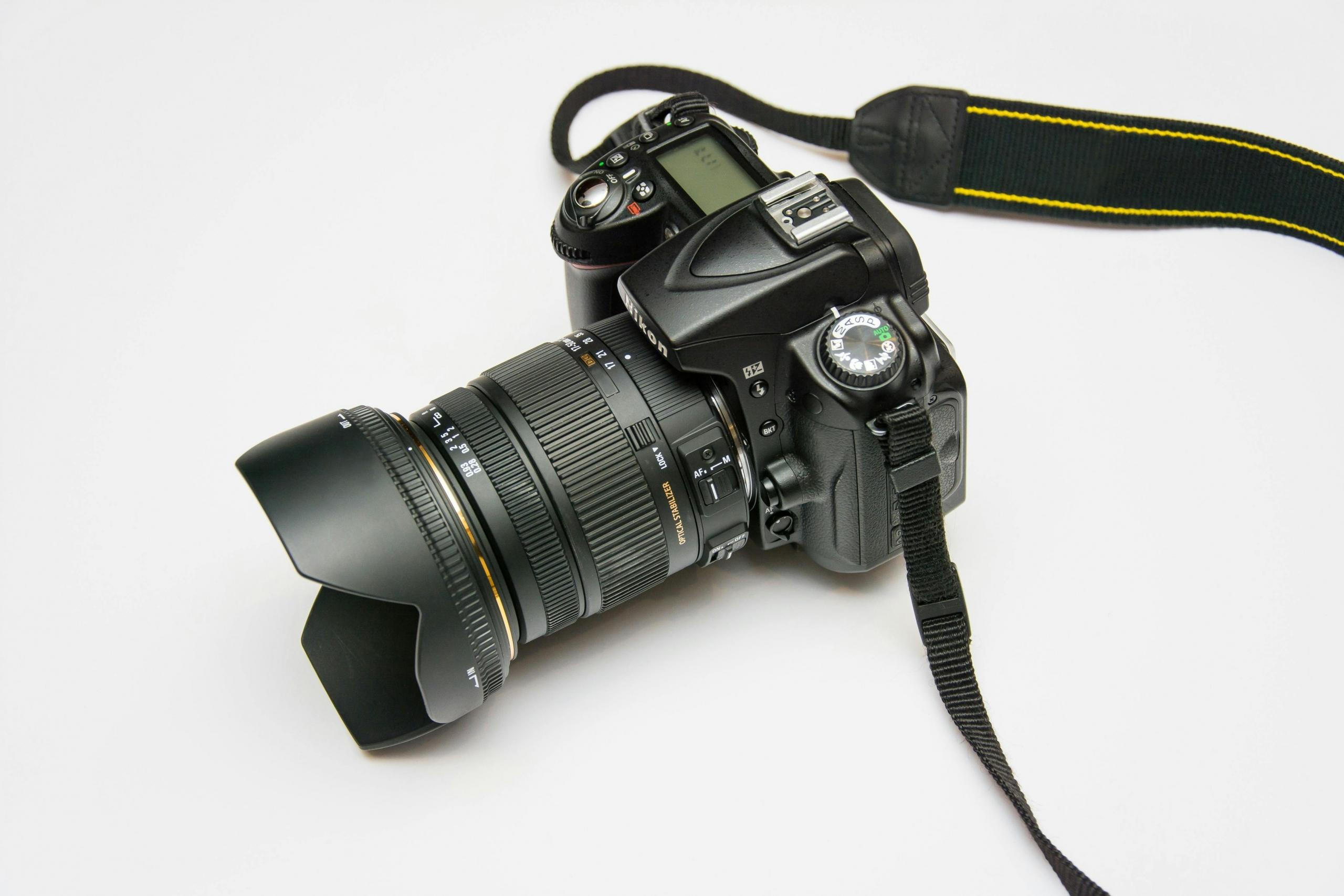 Een digitale SLR-camera met een groot zoomobjectief op een neutrale achtergrond.