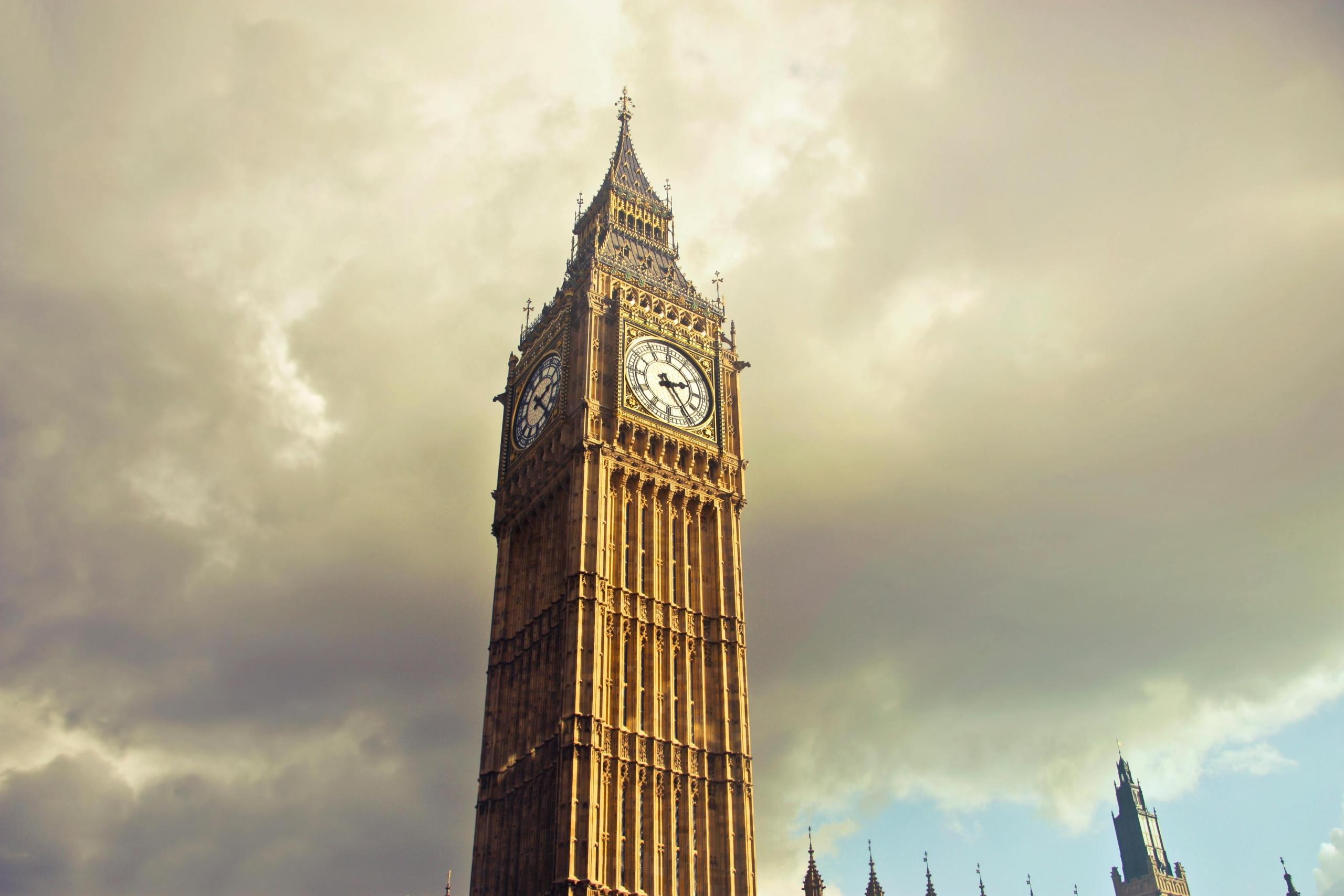 De Big Ben tegen een dramatische lucht, badend in zonlicht.