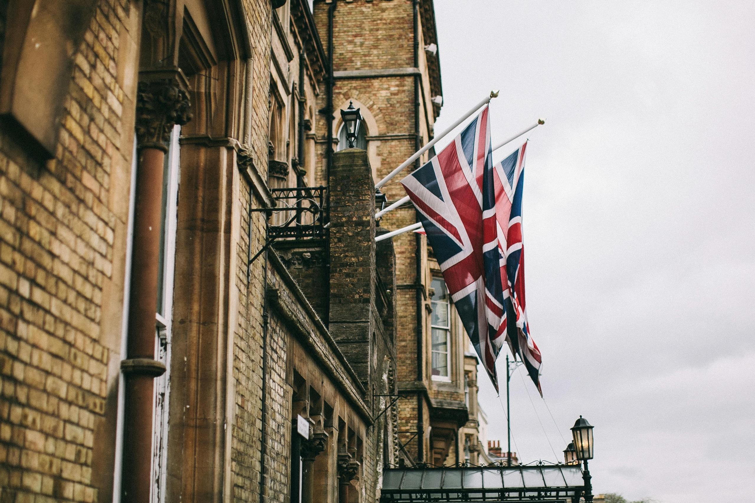 Meerdere Britse vlaggen hangen buiten aan een gebouw, wapperend in de wind.