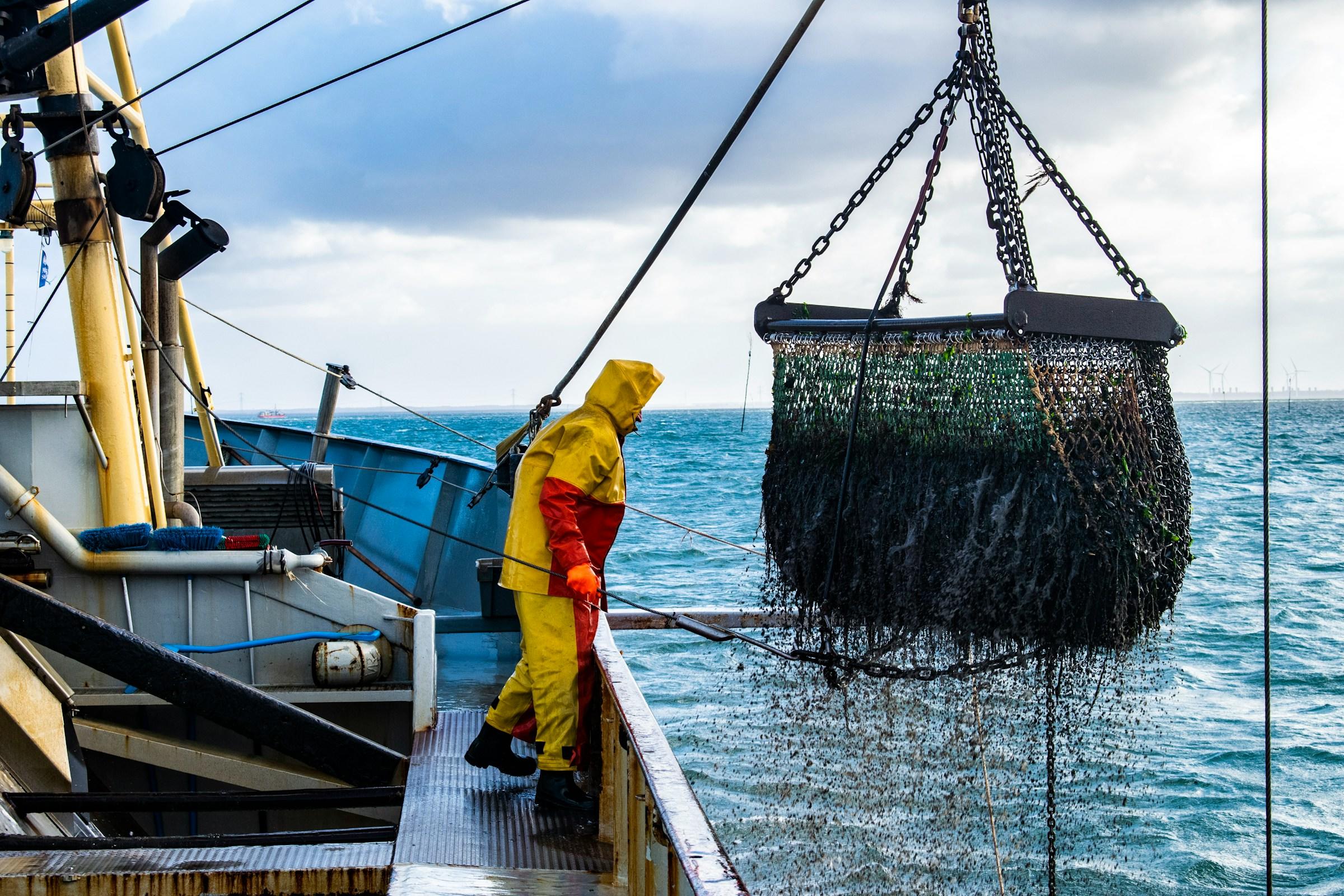 Boot met persoon en groot vissersnet aan takel