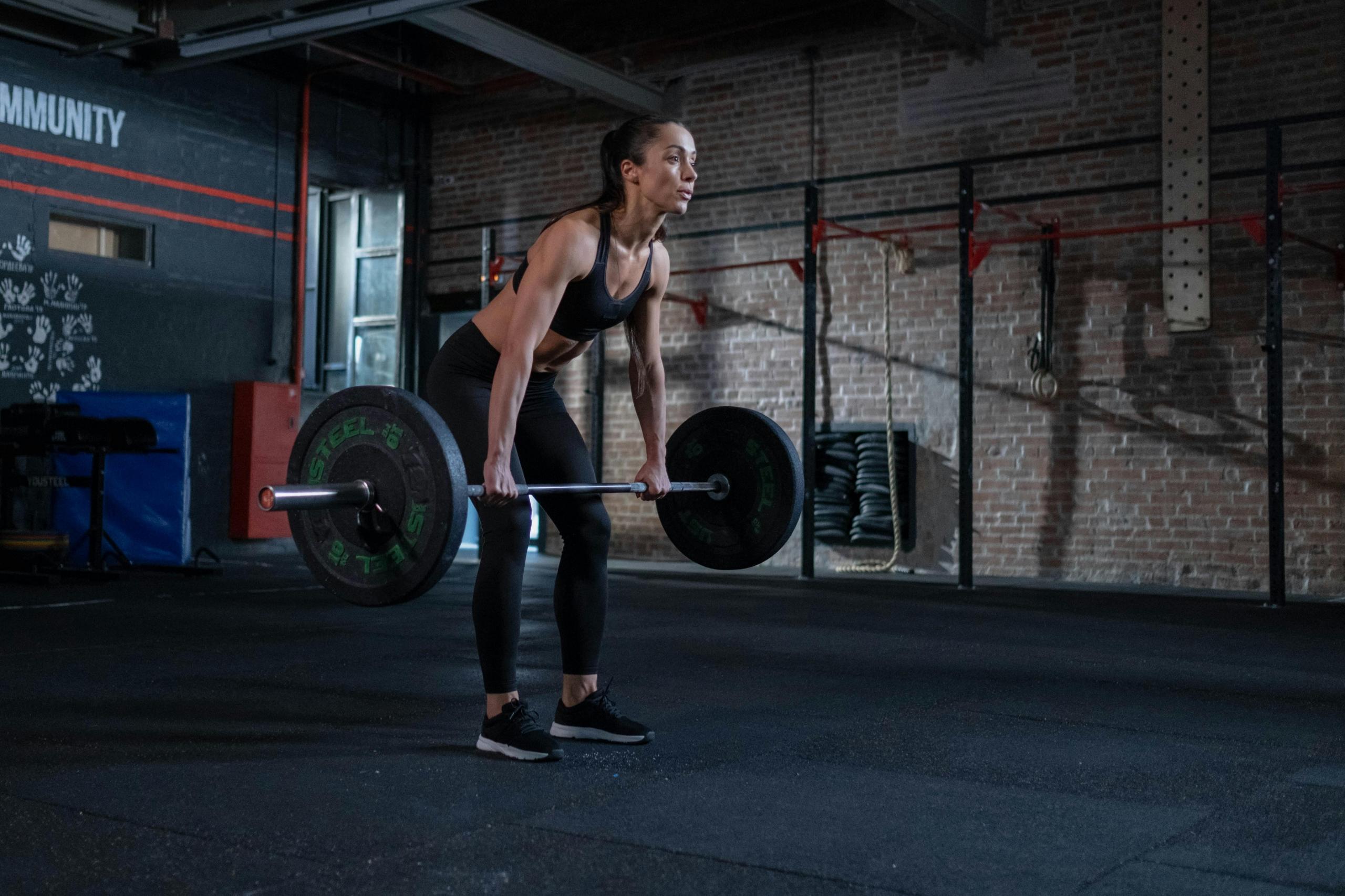 Een vrouw doet deadlifts in een crossfit gym.