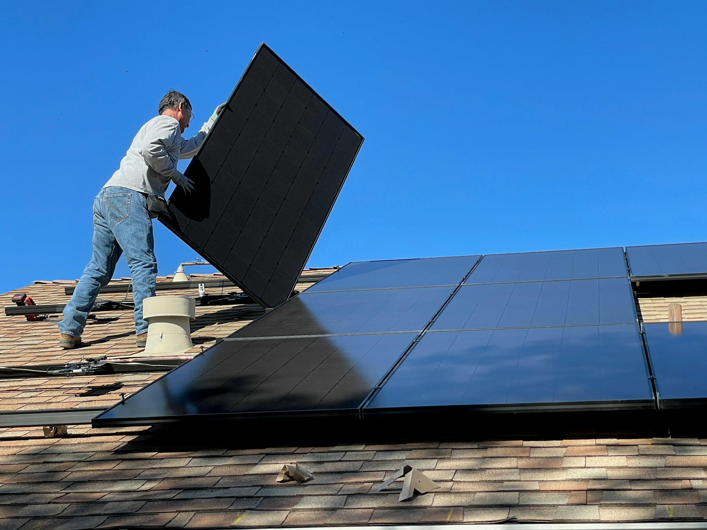 Persoon plaatst zonnepanelen op dak