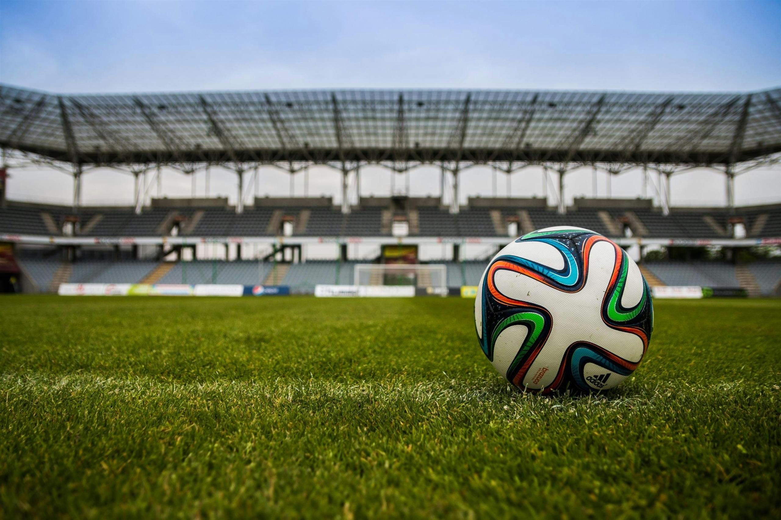 Een Adidas voetbal op een grasveld in een leeg stadion.