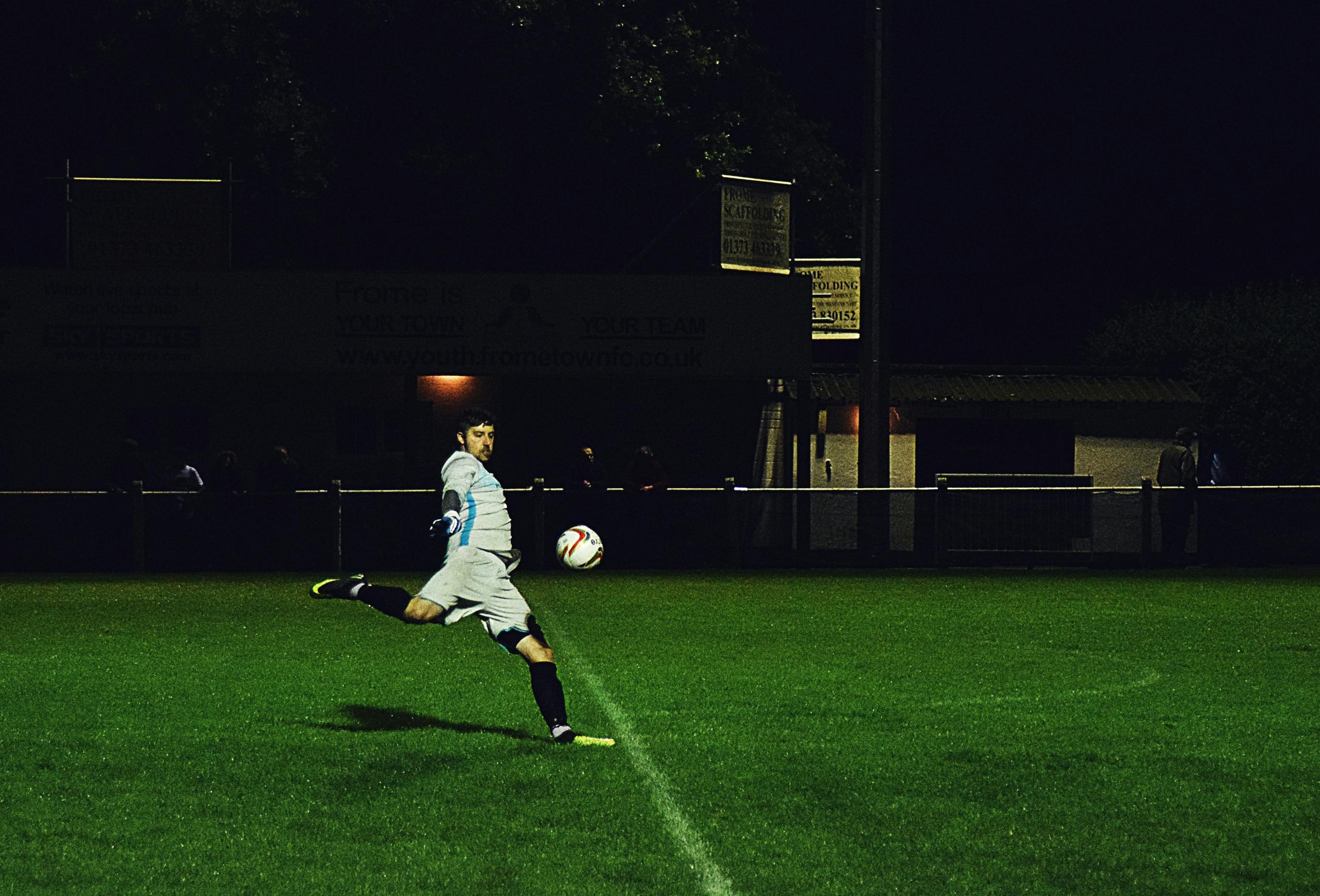 Een keeper in actie tijdens een nachtelijke wedstrijd.