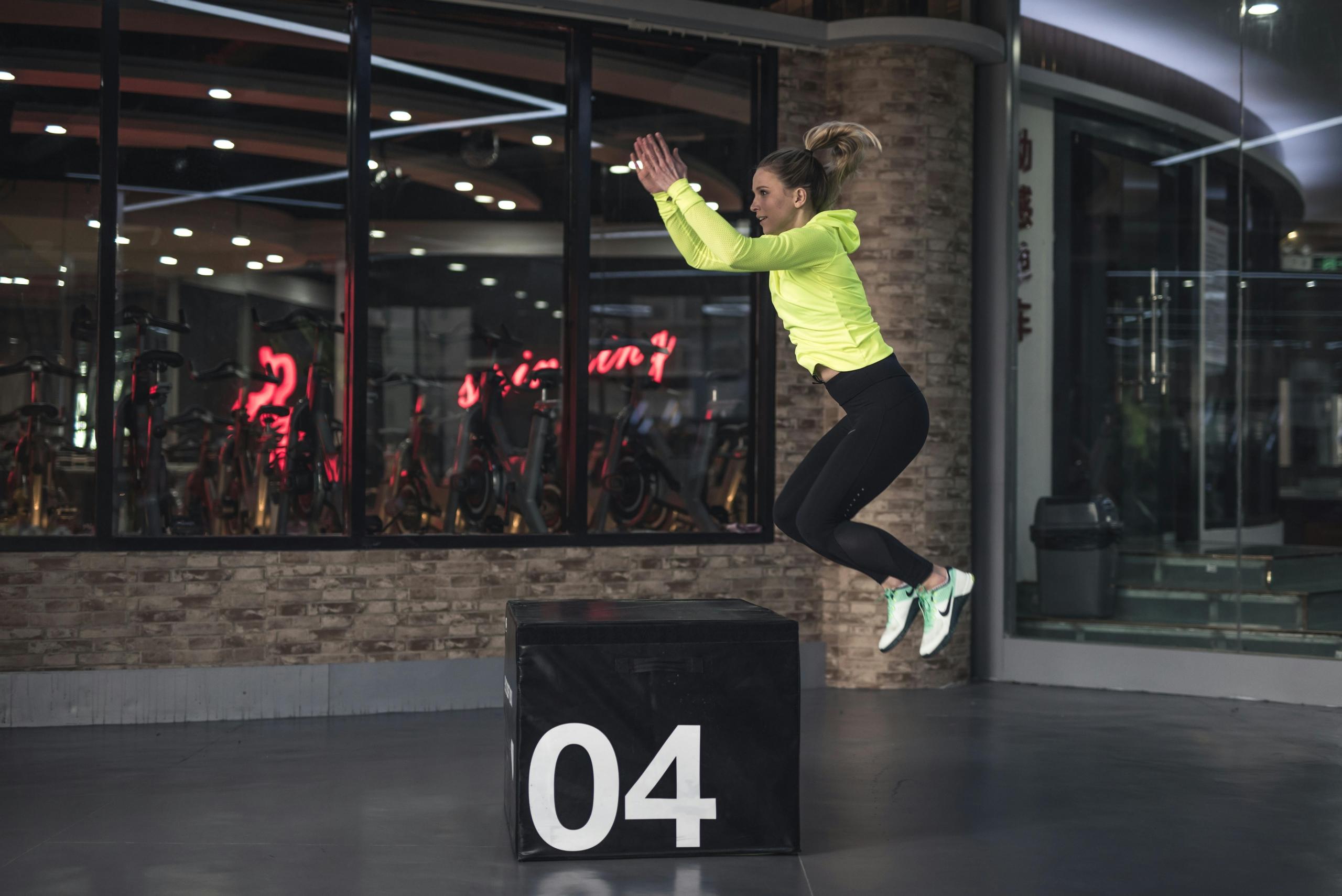 Een vrouw die een box jump uitvoert in de sportschool.