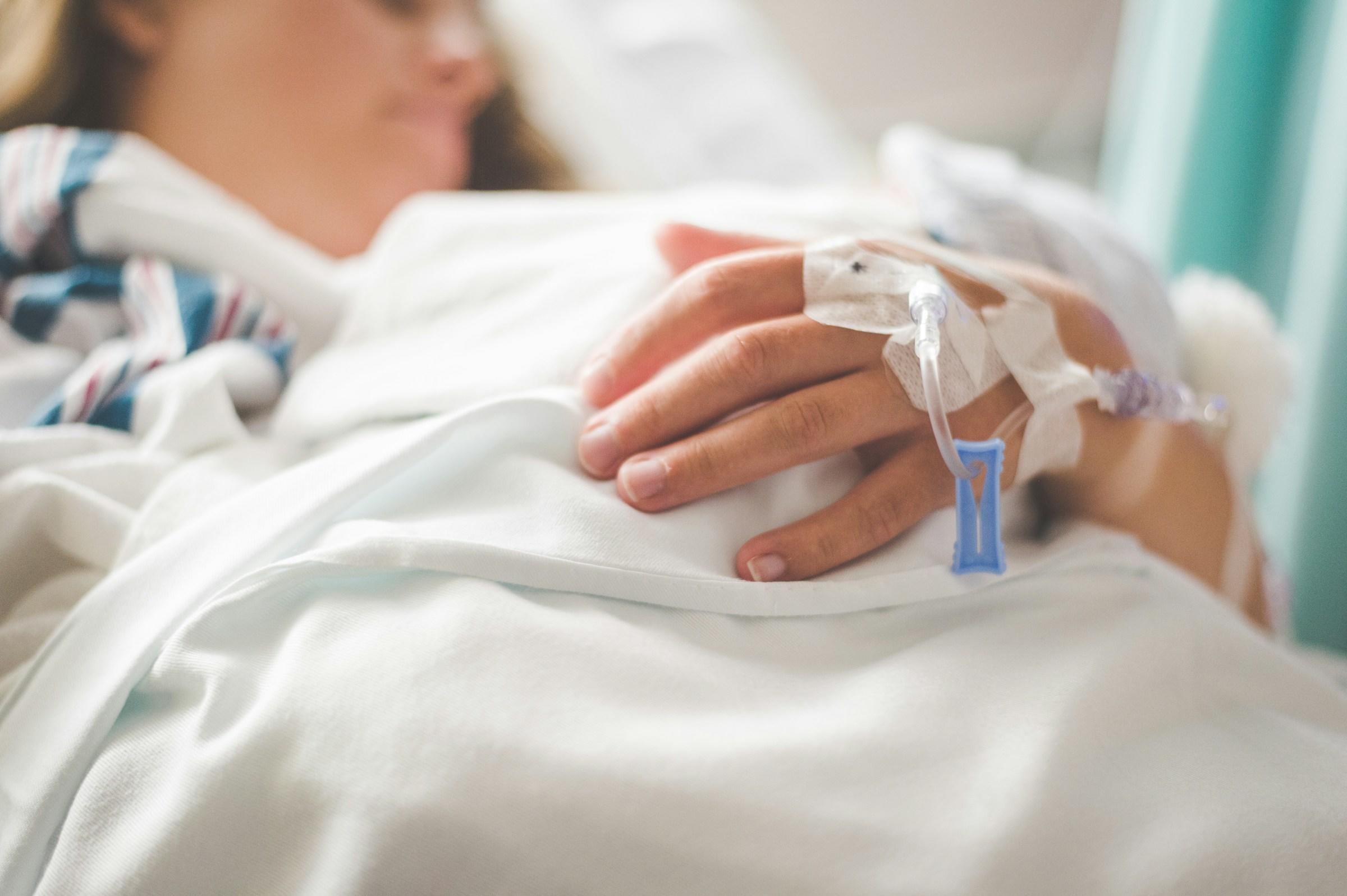 Persoon in bed met infuus in hand