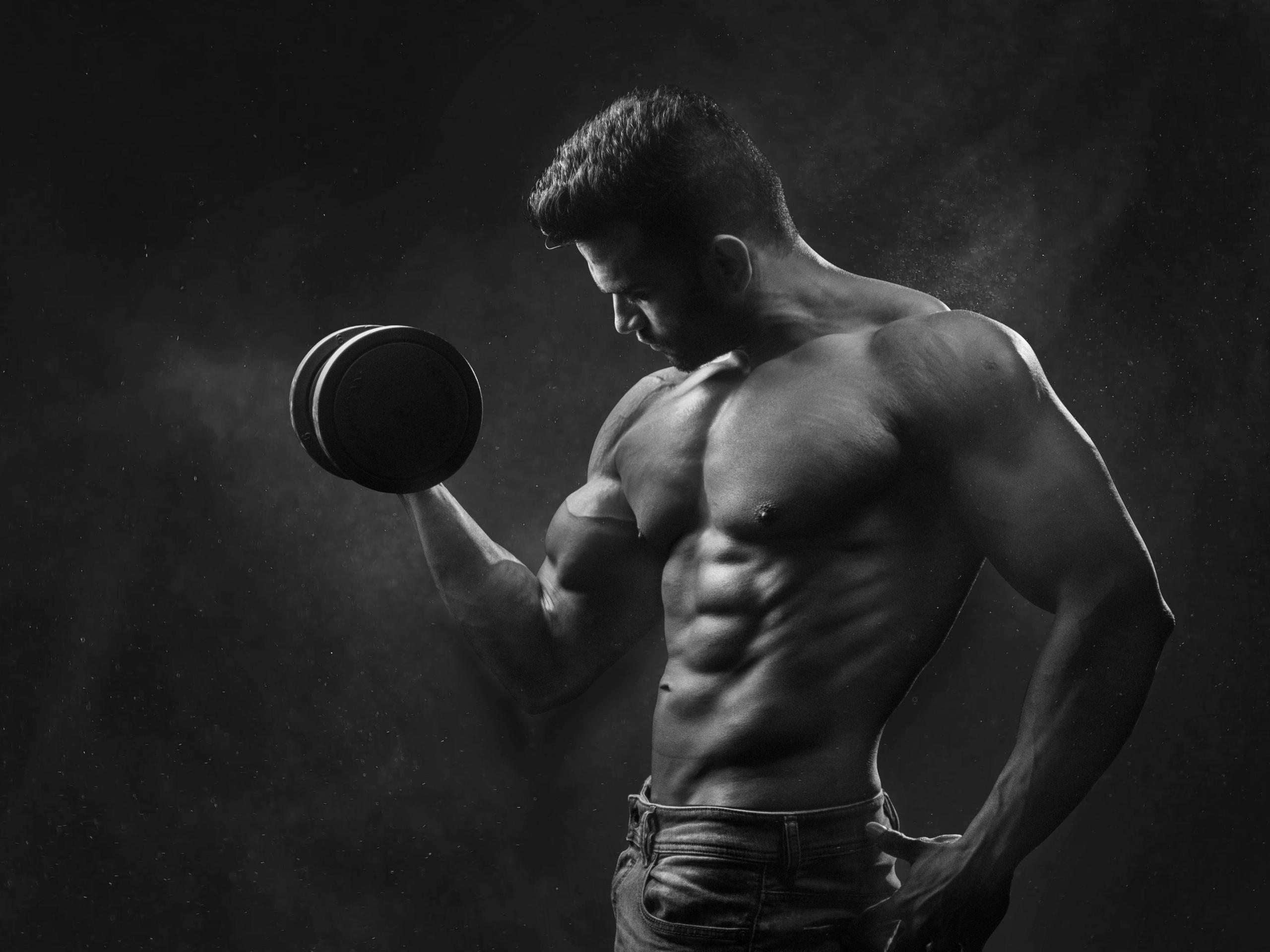 Een bodybuilder doet een bicep curl met een dumbbell.