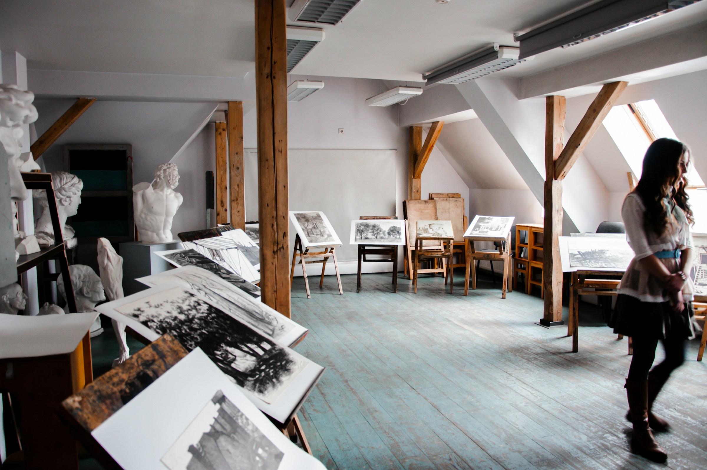 Atelier met tekeningen op tekenezels en persoon op de voorgrond