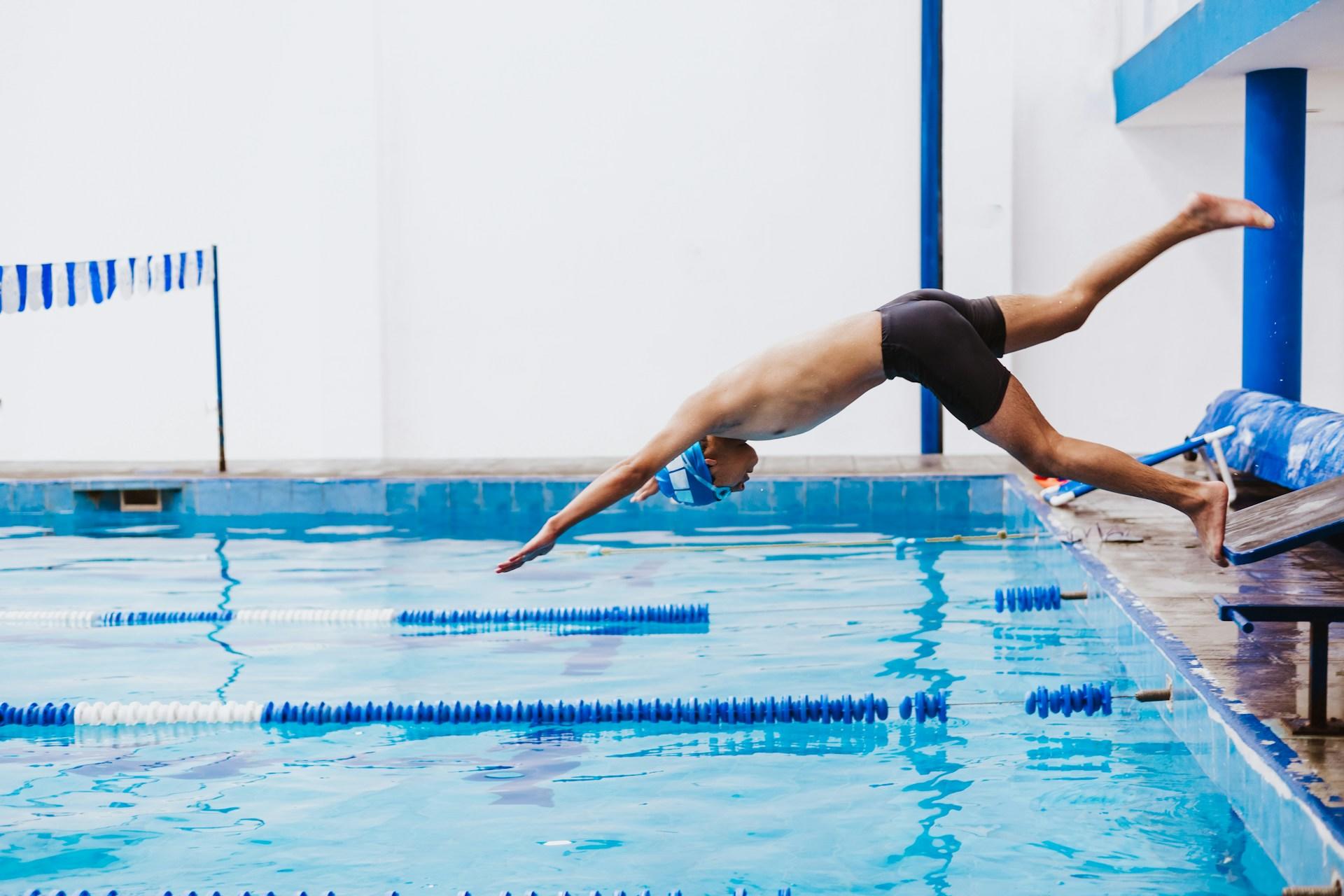 een man springt in het water om te zwemmen