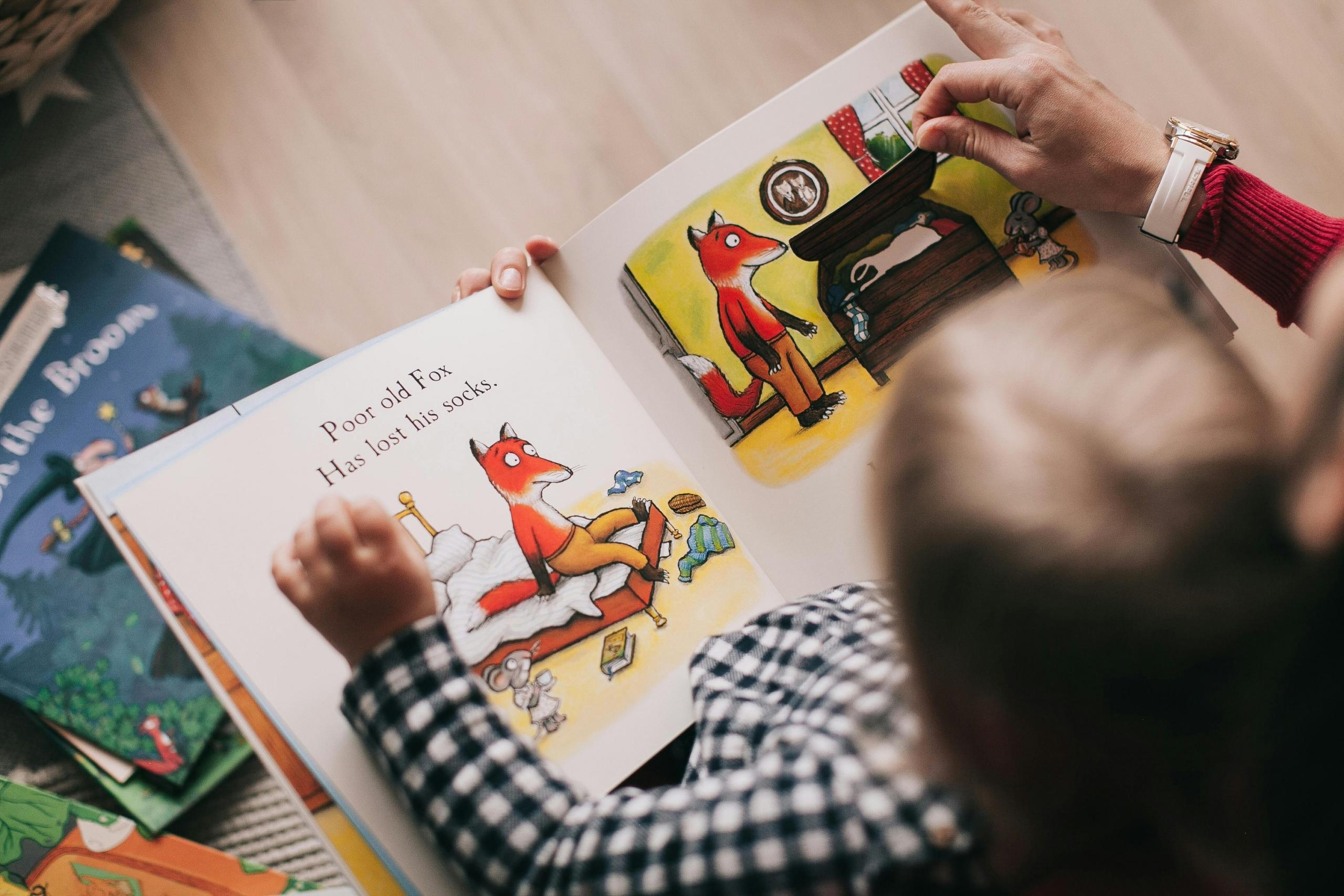 Een volwassene leest een prentenboek voor aan een kind.