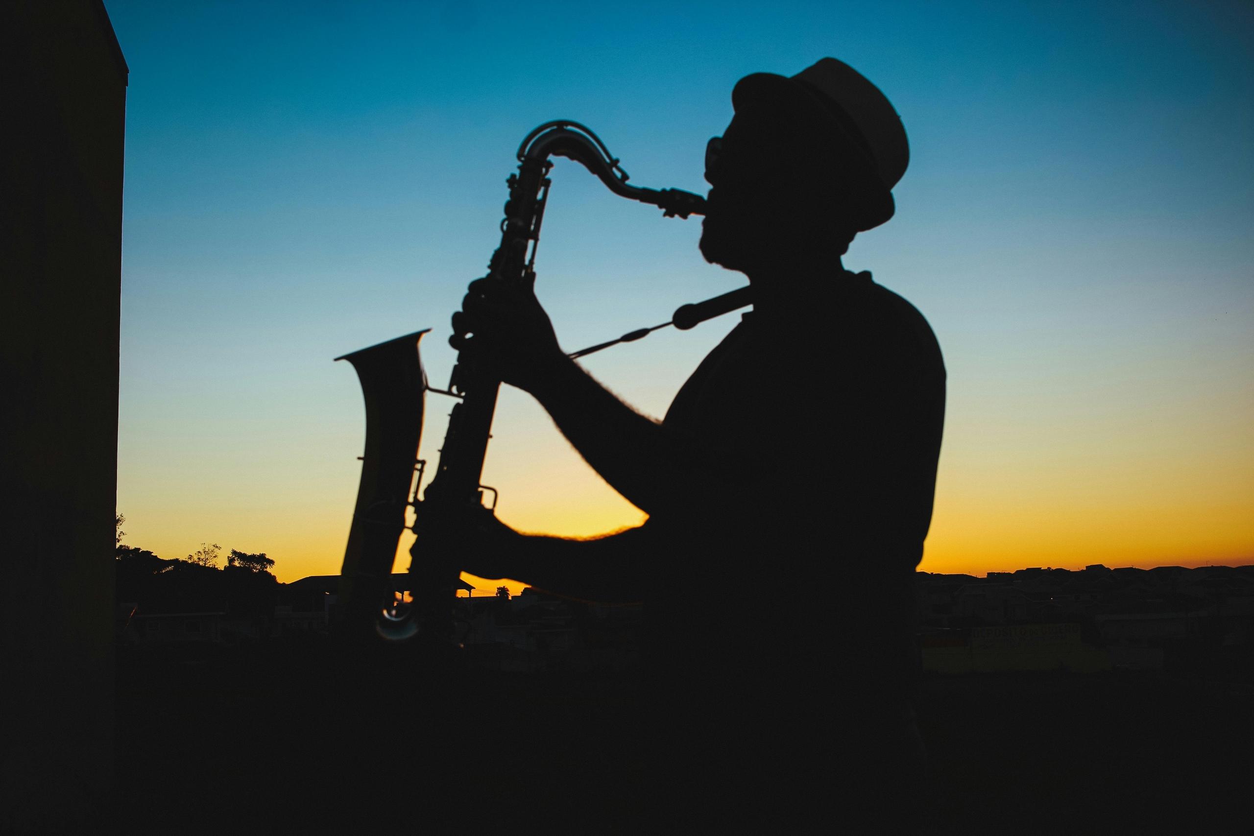 Een silhouet van een saxofonist die speelt bij zonsondergang.