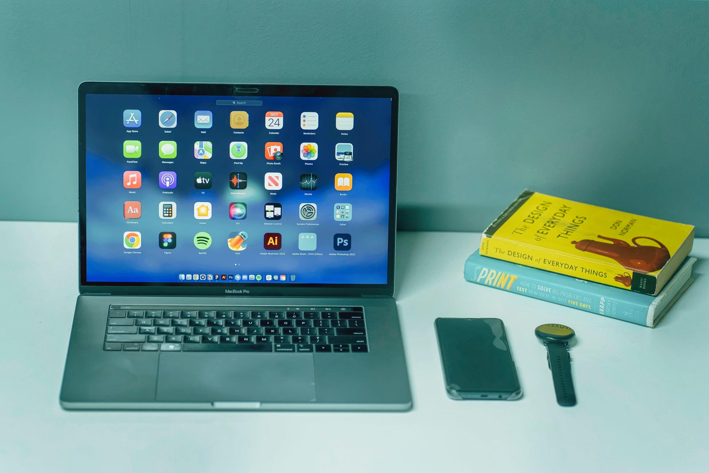 Laptop met iconen, IPhone, horloge en boeken