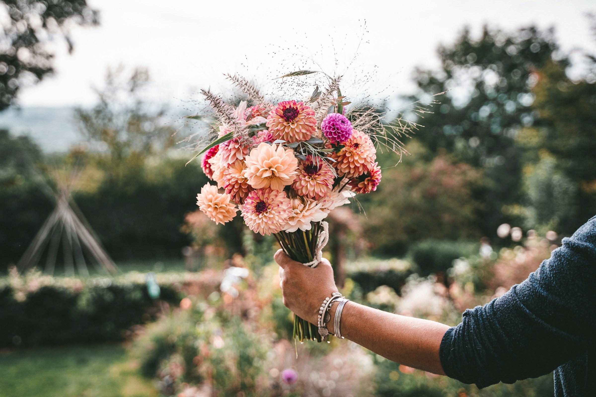 Persoon met bos bloemen in de hand