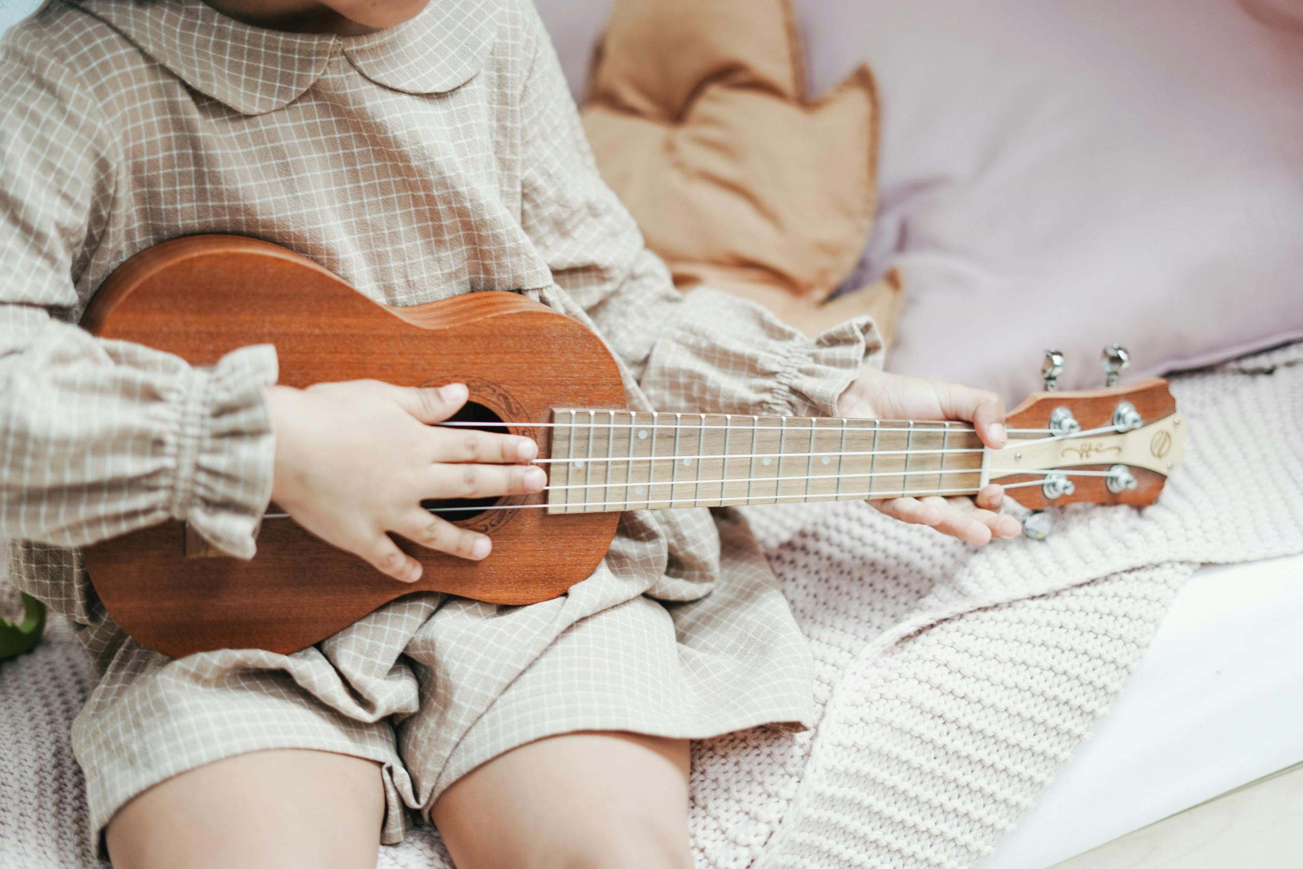 Meisje speelt ukelele in een ontspannen, huiselijke setting.