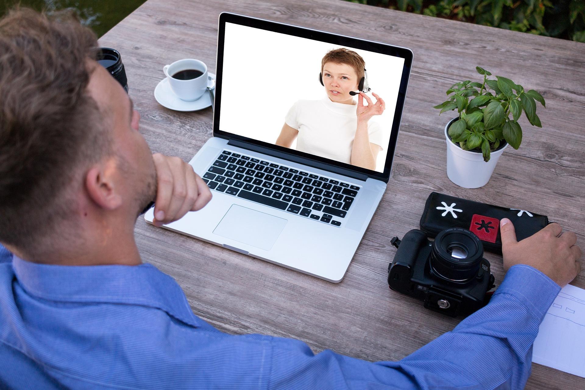 Persoon kijkt naar laptop met persoon op beeldscherm