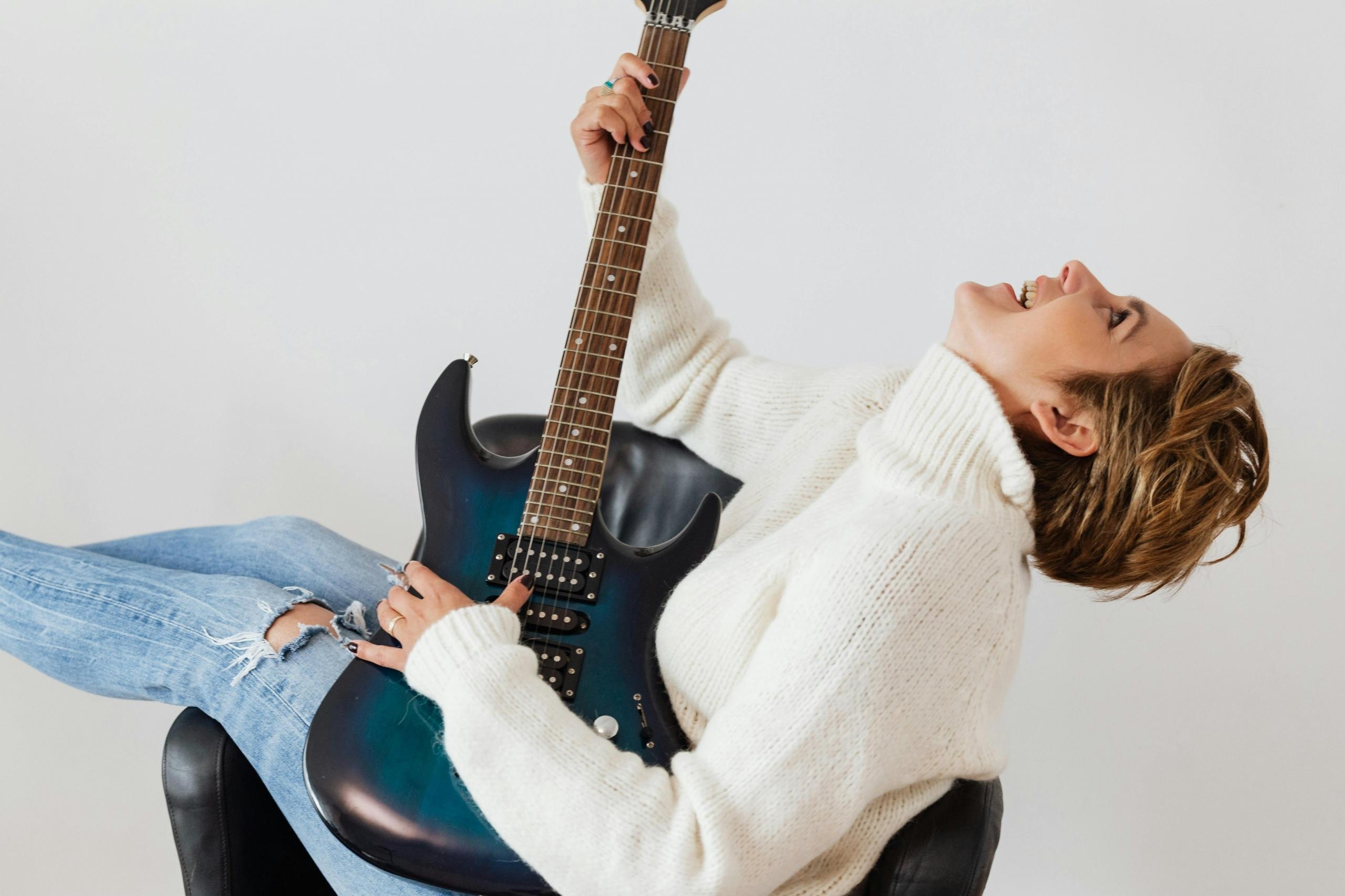 Vrouw speelt elektrische gitaar, ontspannen en vrolijk.