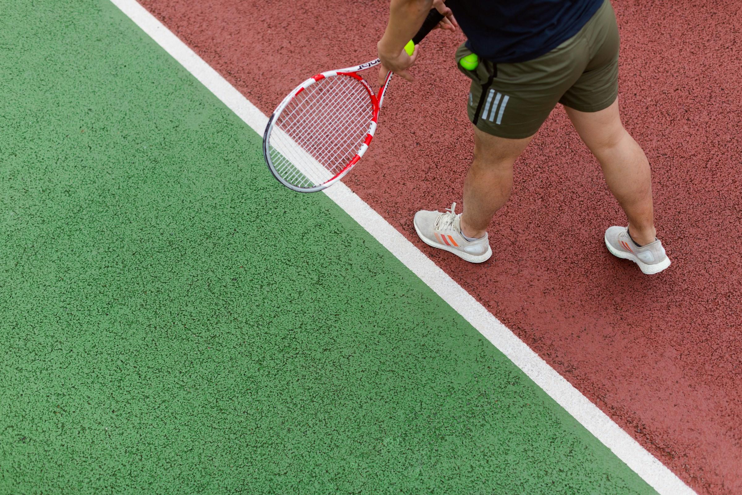 Tennisspeler achter witte lijn