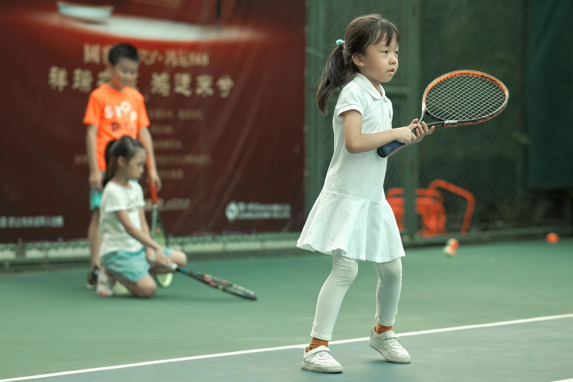 Kind in wit pakje met tennisracket in handen