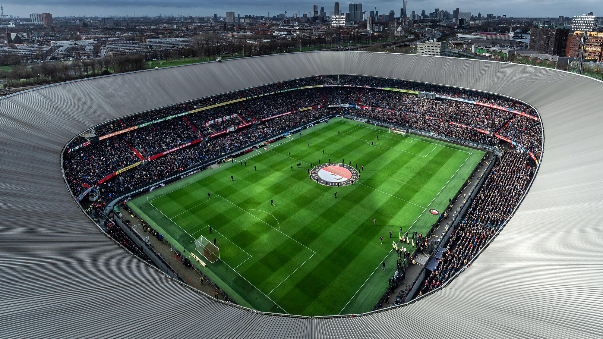 Het iconische Feyenoord-stadion tijdens een belangrijke wedstrijd, omringd door een zee van fans.