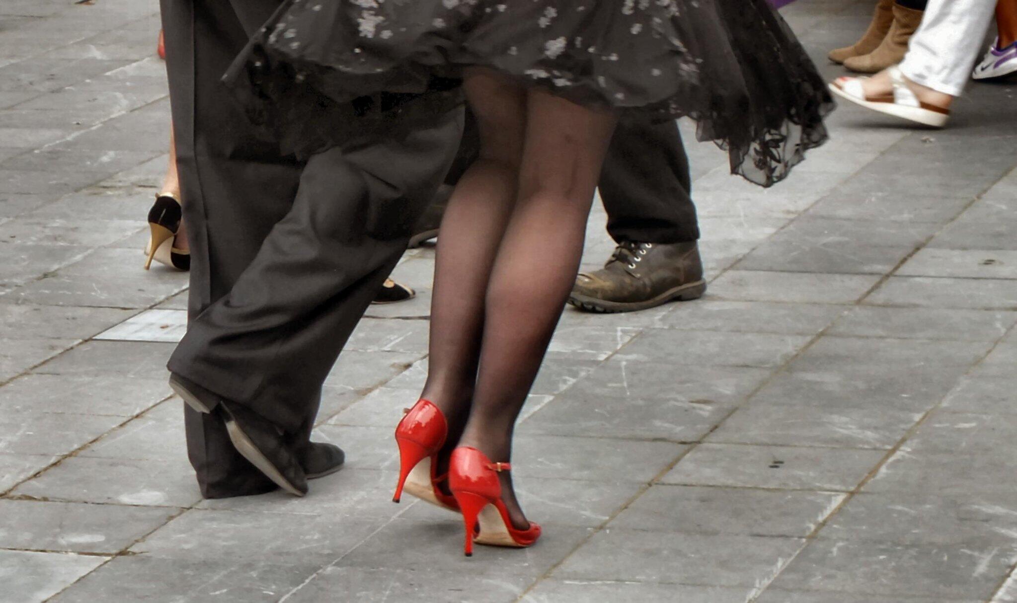 Benen met hooggehakte rode schoenen en benen zwarte platte schoenen