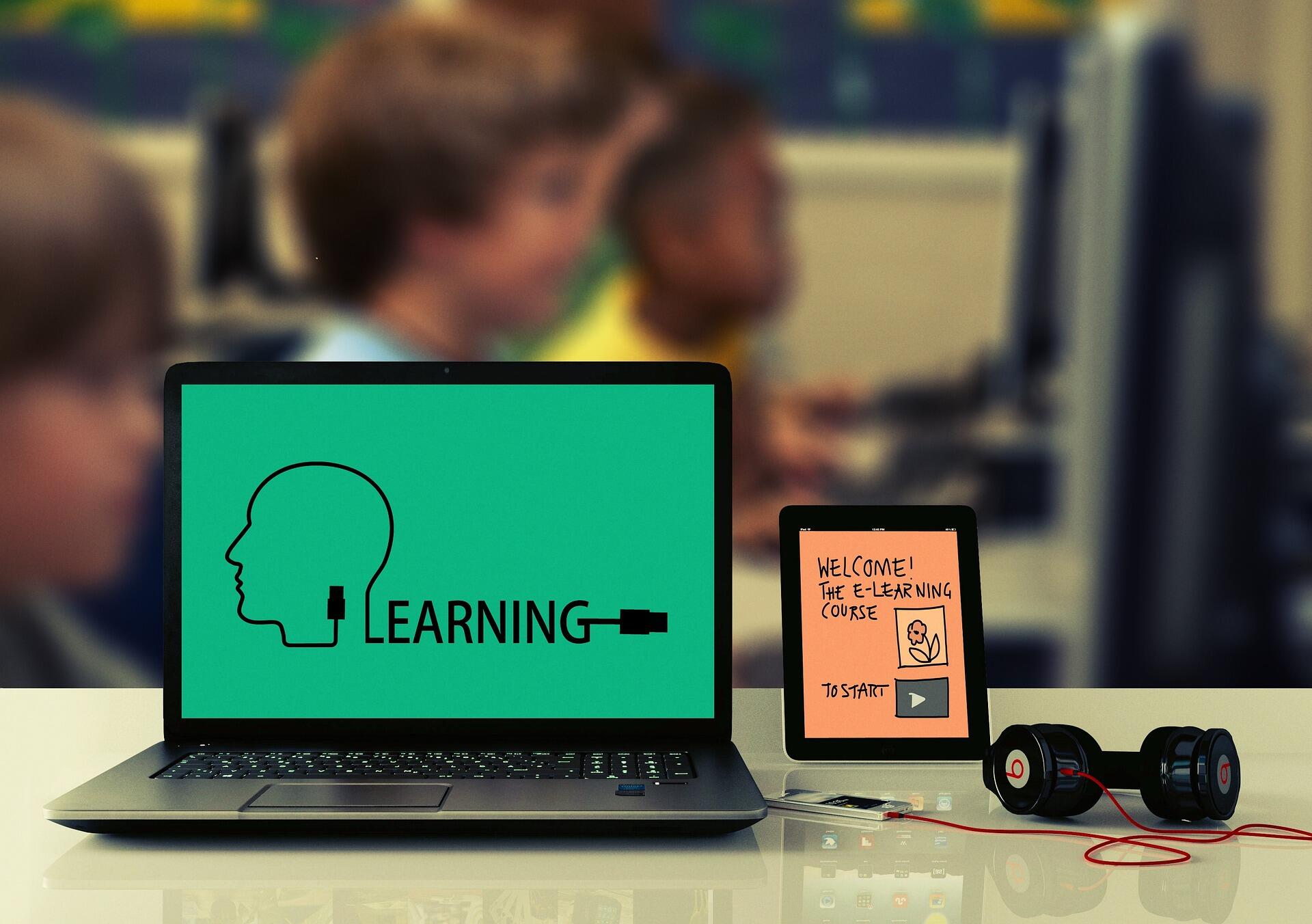 Laptop, tablet, iPhone en koptelefoon aangesloten op E-Learning