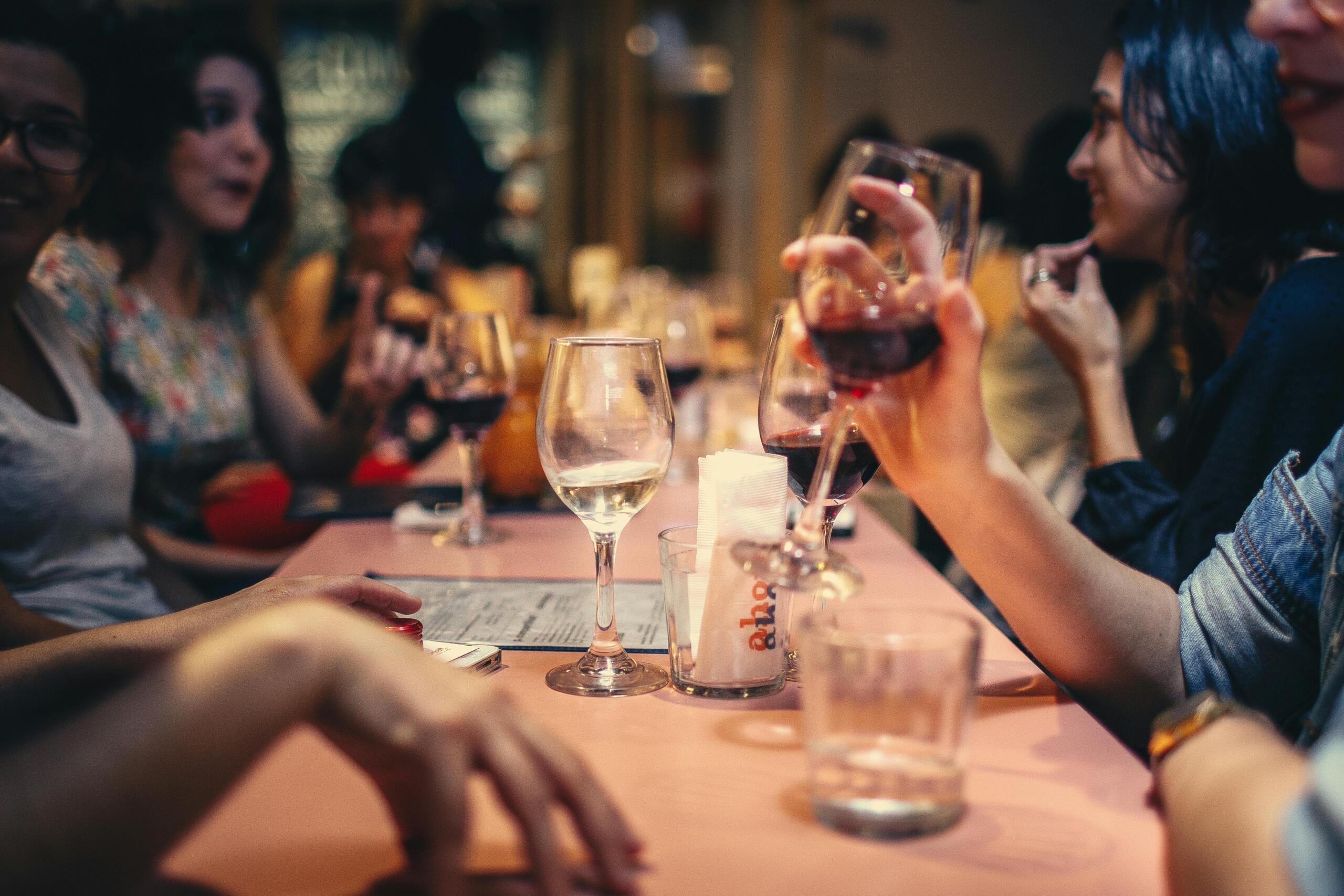 Een groep mensen geniet van een gezellige bijeenkomst met glazen wijn op tafel.