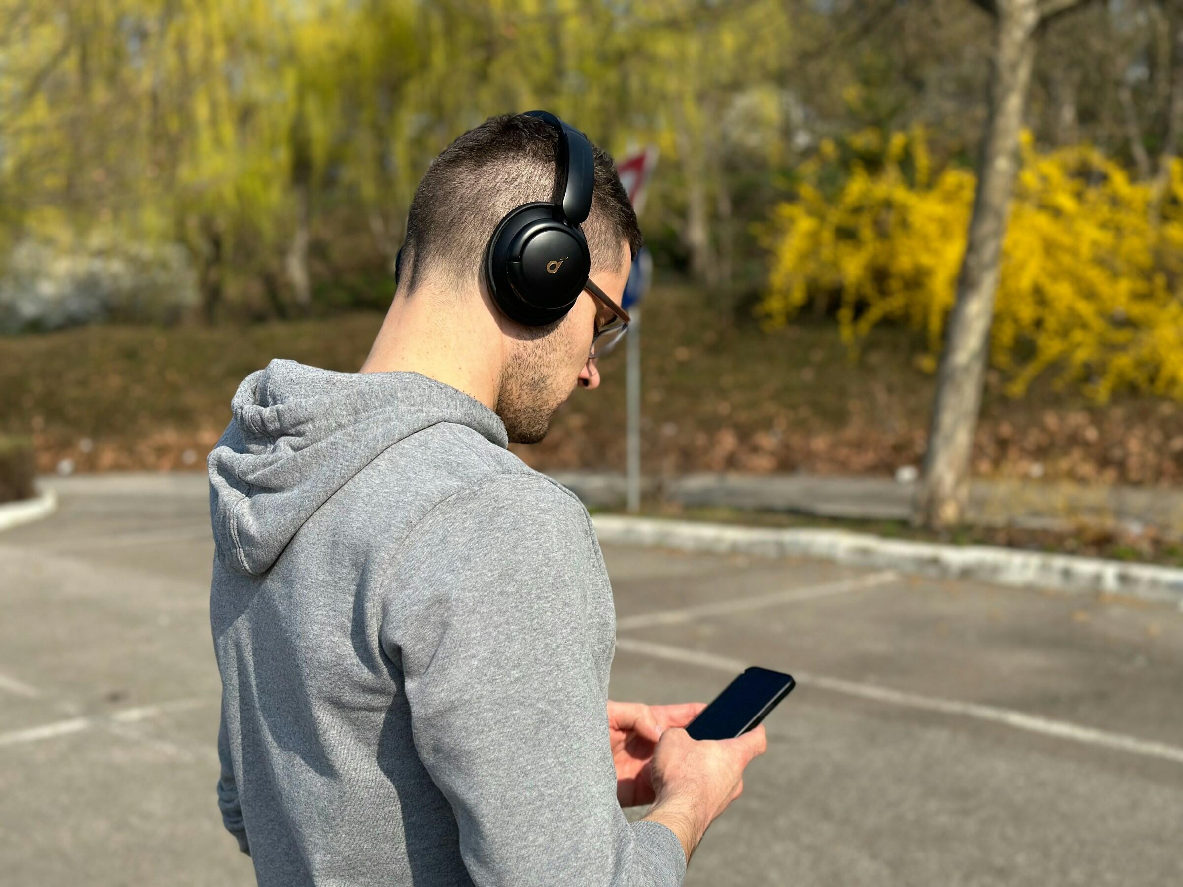 Persoon met koptelefoon op en iPhone in handen