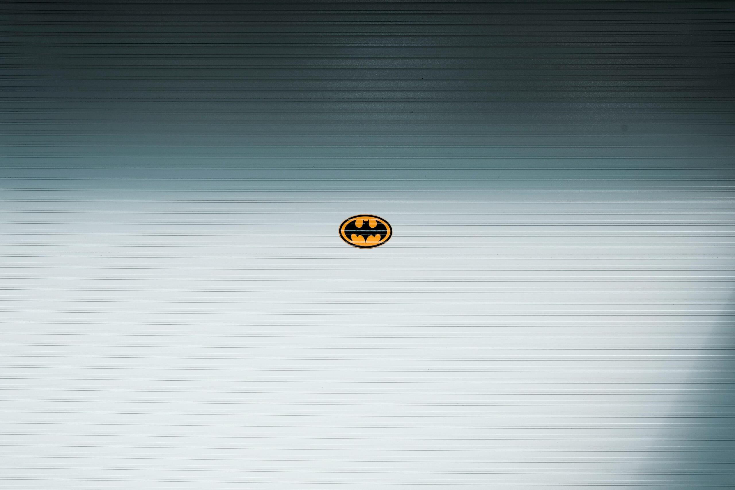 Een minimalistisch beeld van een Batman-logo op een groot metalen oppervlak.