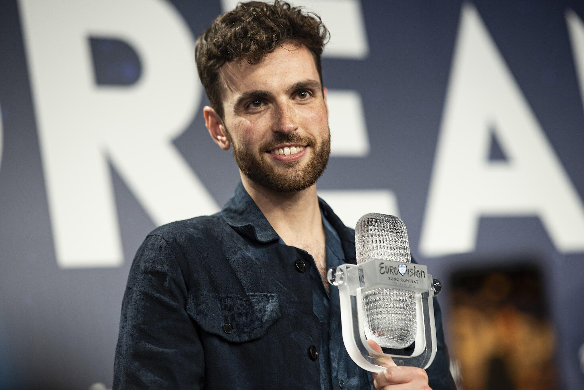 Lachende persoon met microfoon waarop Eurovision staat