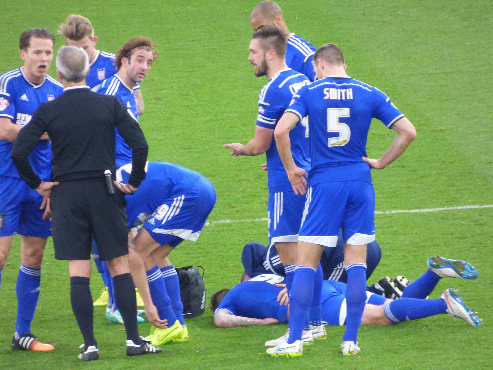 Aantal personen in een blauw tenue en een persoon in een zwart tenue