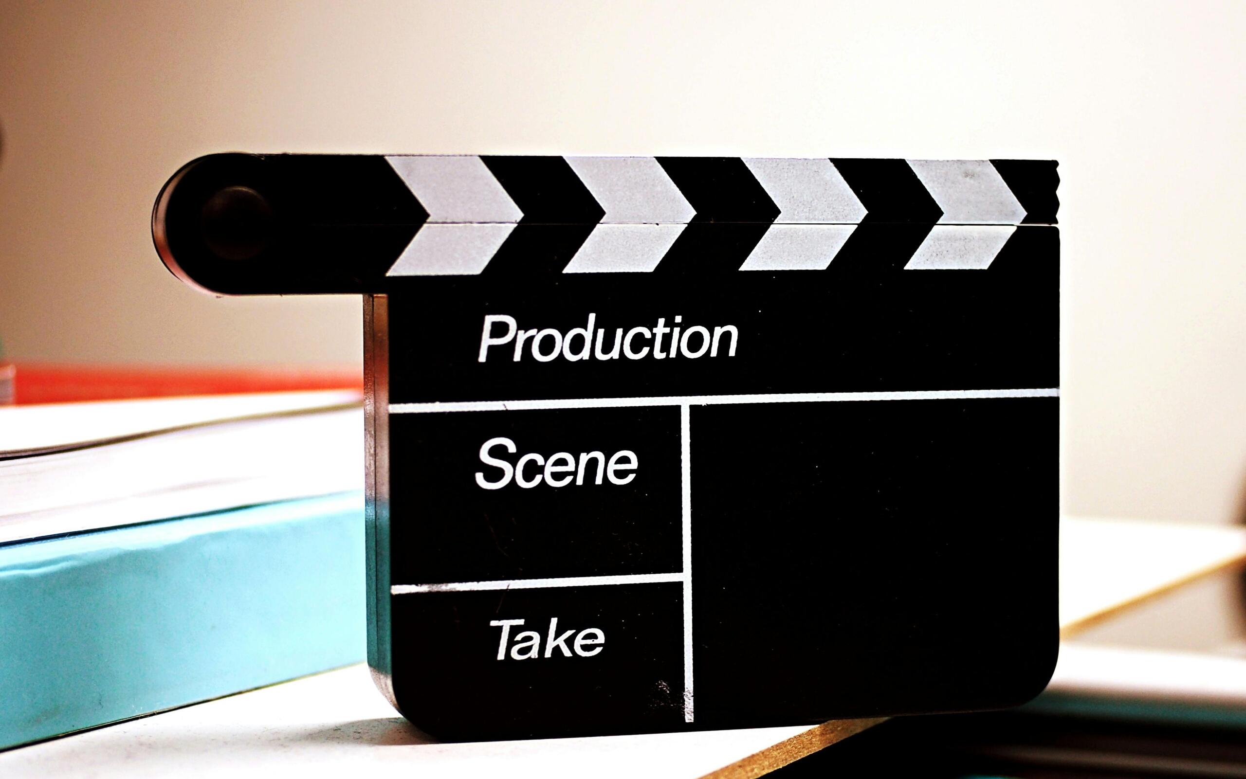 Close-up van een zwarte filmklapper met de woorden "Production", "Scene" en "Take".
