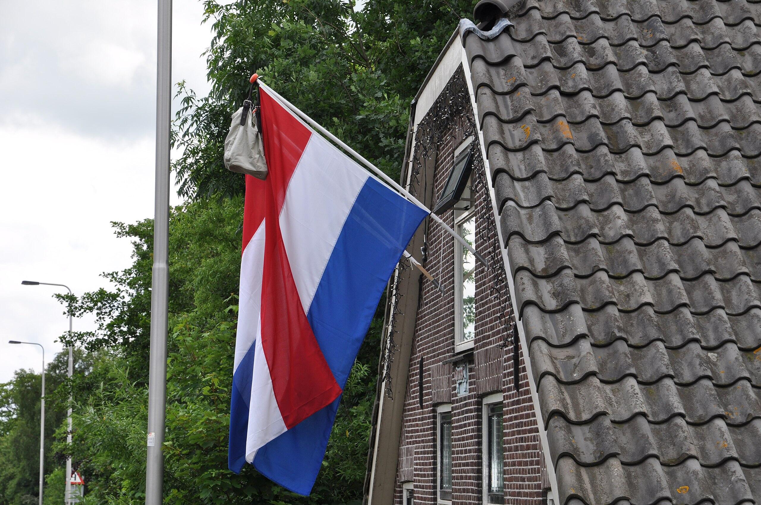 Uitgestoken Nederlandse vlag met tas aan huis