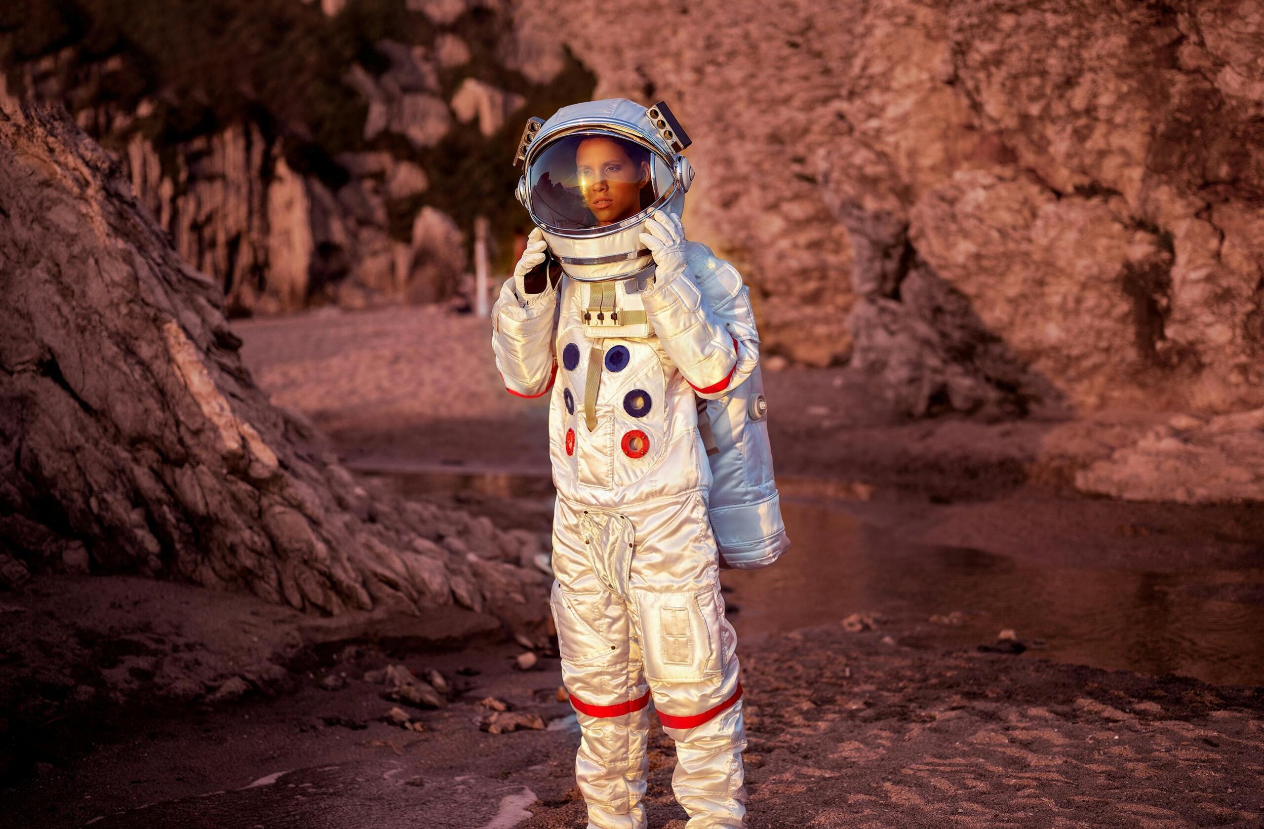 Astronaut in zilveren pak op een rotsachtig buitenaards landschap
