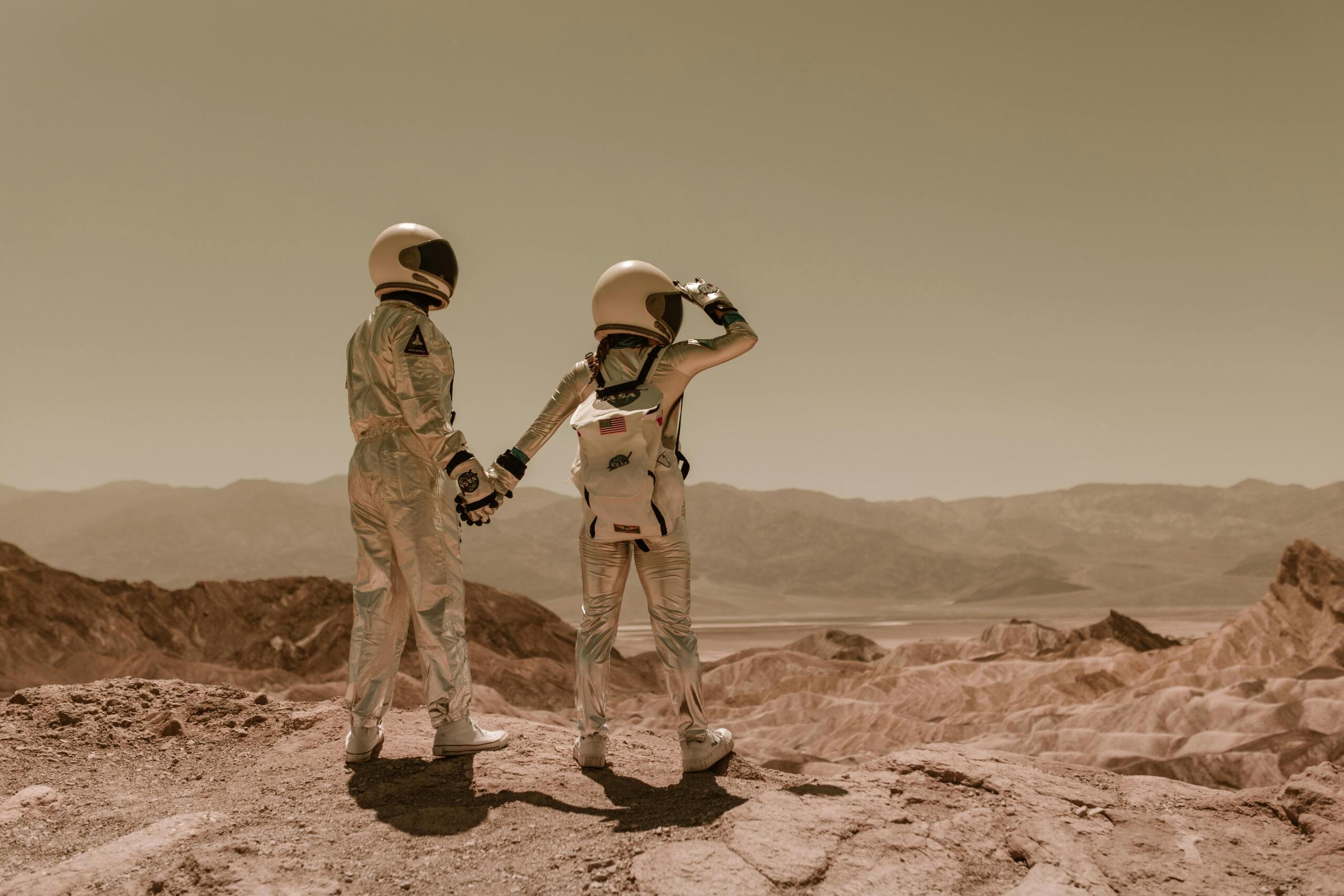 Twee astronauten hand in hand in een woestijnachtig gebied