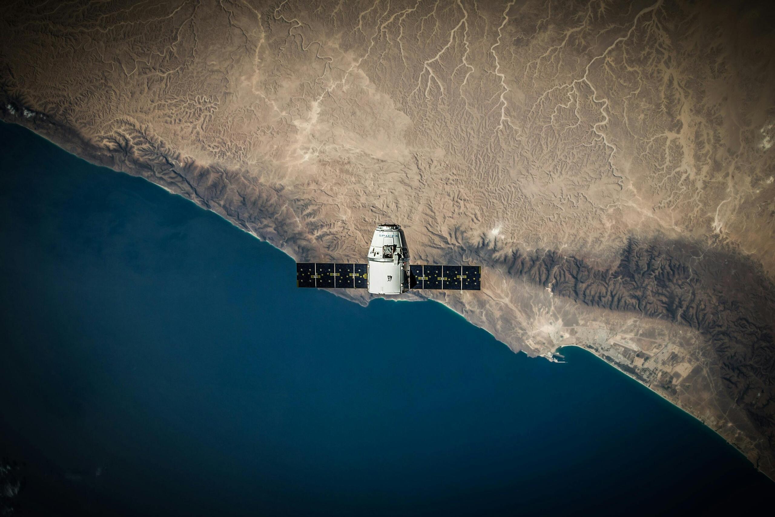 SpaceX Dragon-capsule zweeft boven de aarde met zicht op een kustlijn.